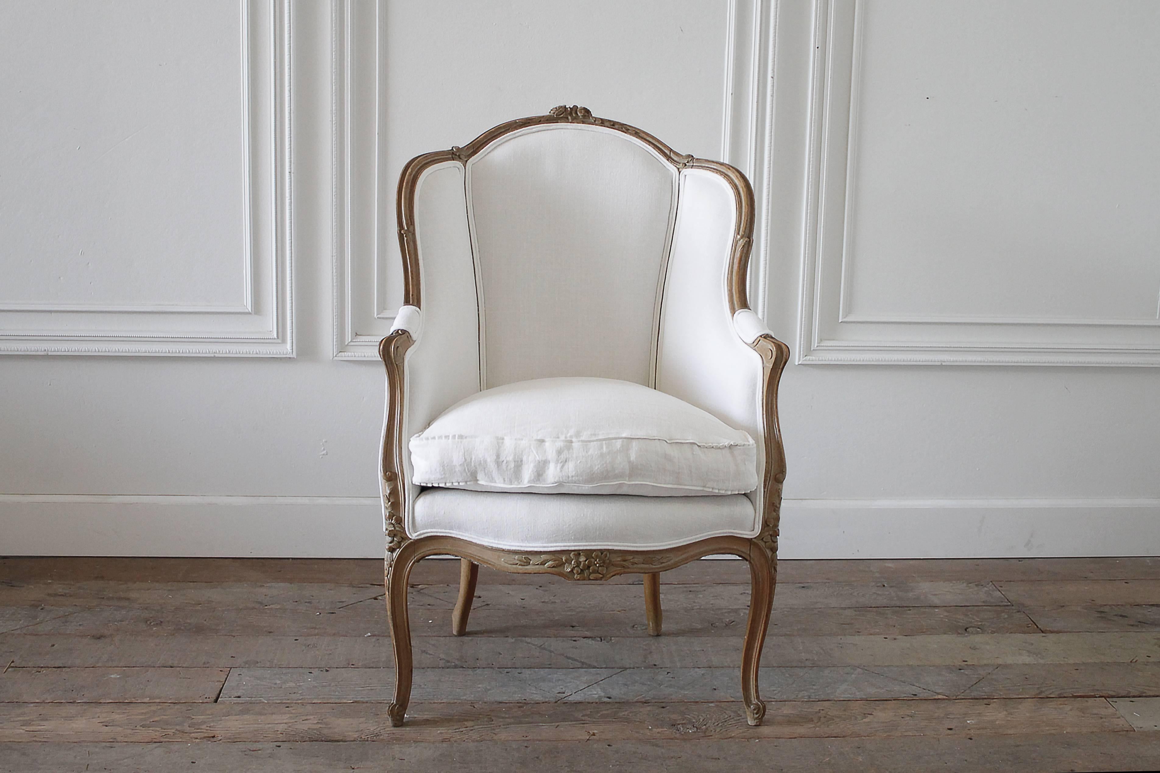 Beautiful antique French wing back style chair with original wood finish. Wood look to be a beechwood in a medium honey color. Carved roses at the top, with Classic Louis XV carved legs. Upholstered in our pre washed 100% organic Irish linen in soft