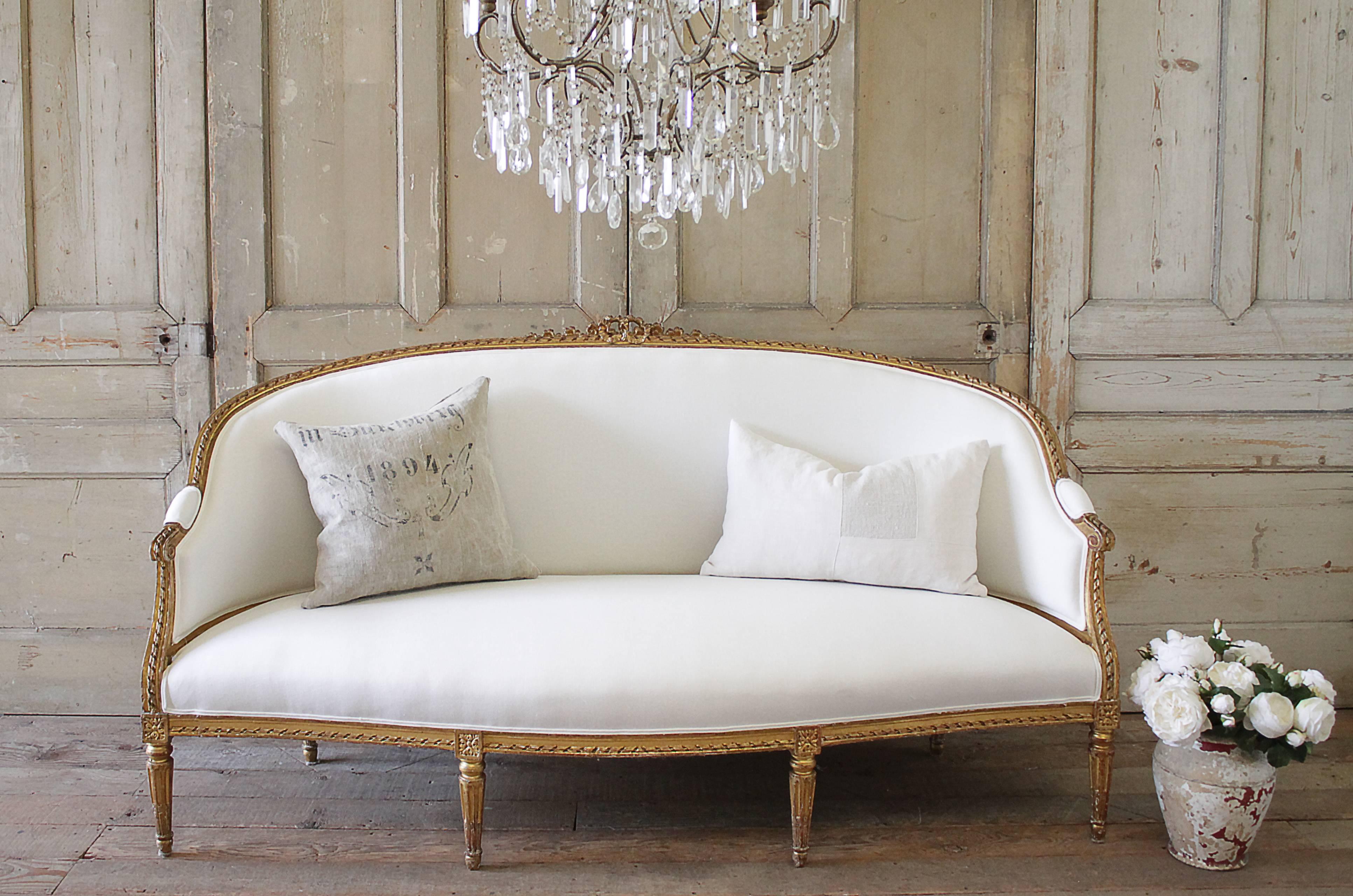 Beautiful large giltwood sofa with ribbon carved crest. Original finish has a wonderful aged patina, gilt has slight distressed edges. We have reupholstered this sofa in our 100% soft white Belgian linen. Linen has been prewashed, and has a soft