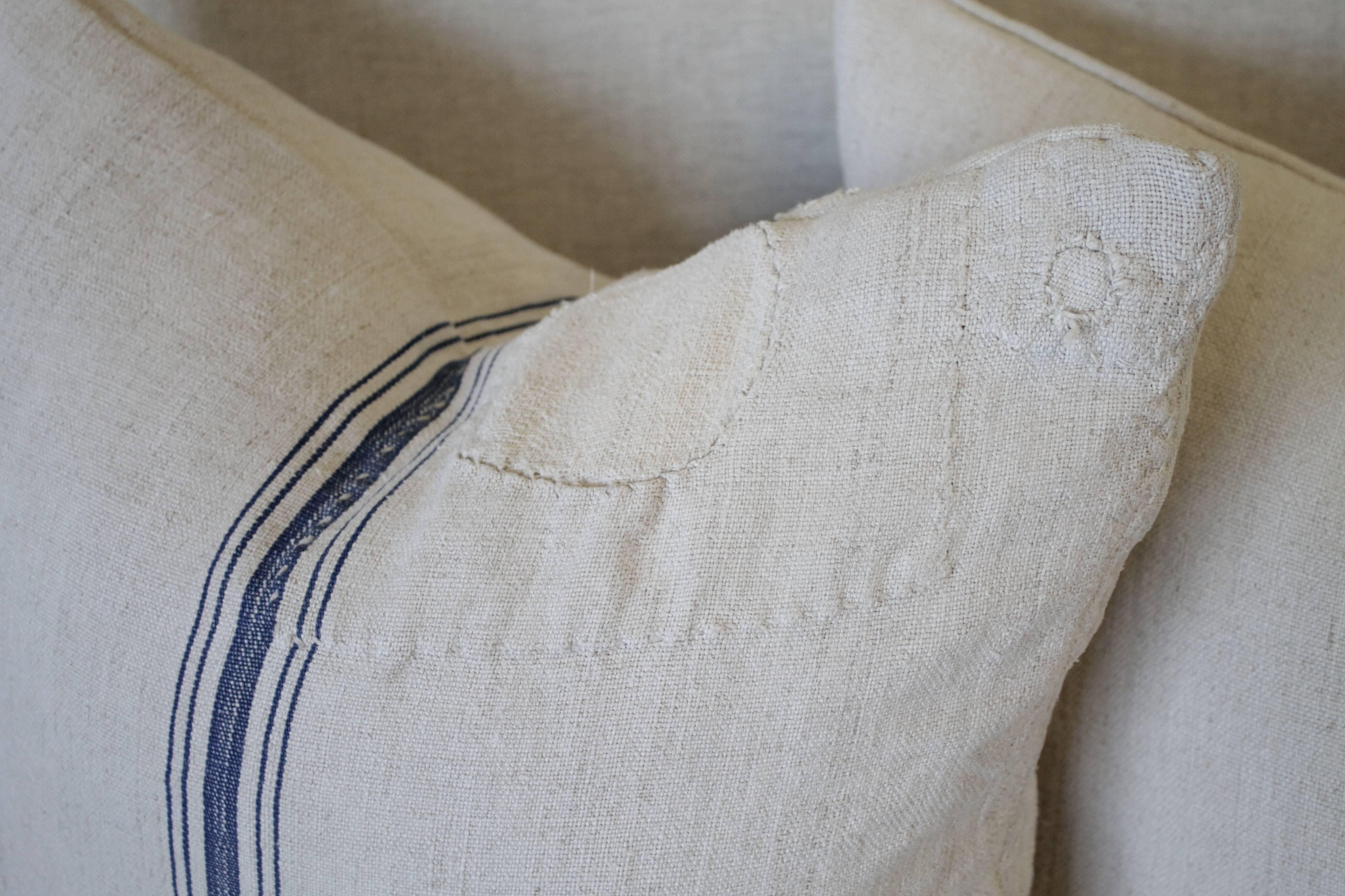 We make these pillows from old grain sacks from Eastern Europe. The pair have a deep blue triple stripe down the center, and the body is a medium oatmeal color. They are sewn with a zipper closure, and since we prewash all our vintage fabrics in a