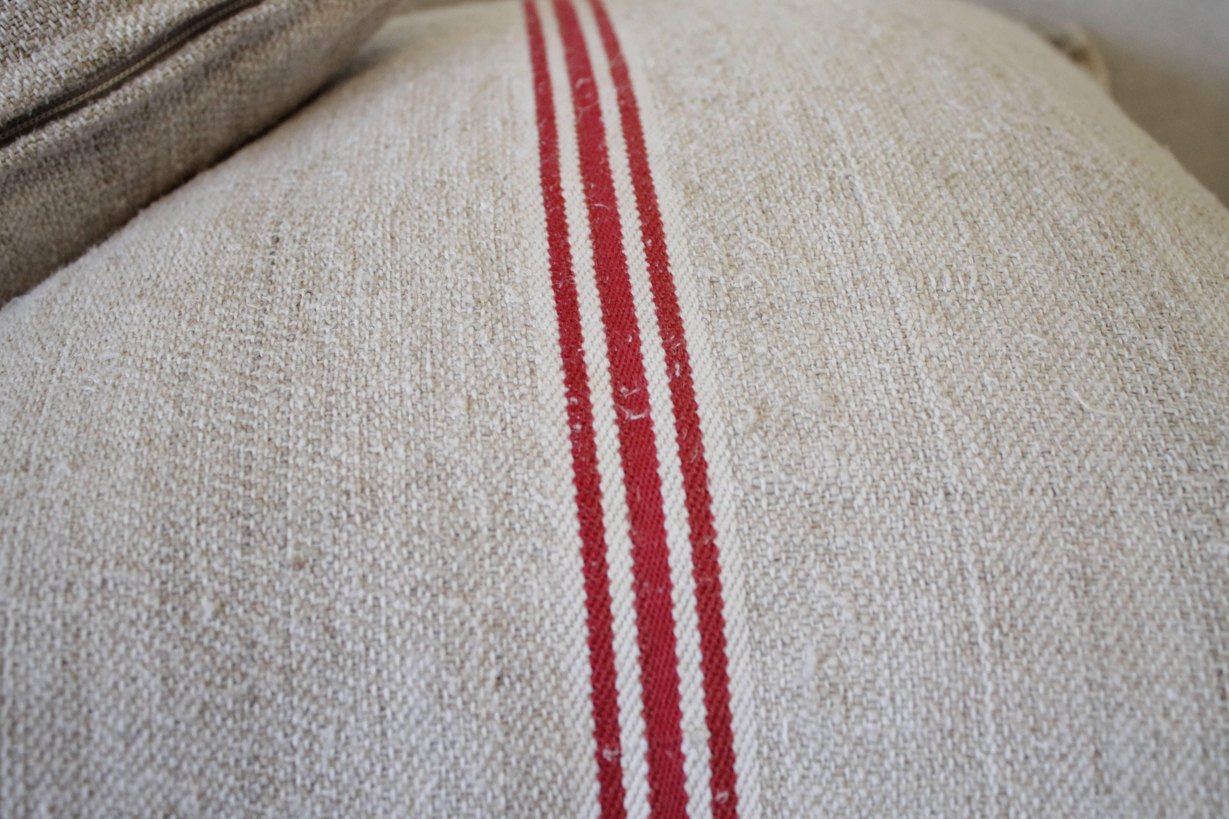 We make these pillows from old grain sacks from Eastern Europe. The pair have a deep red triple stripe down the center, and the body is a medium oatmeal color. They are sewn with a zipper closure, and since we prewash all our vintage fabrics in a