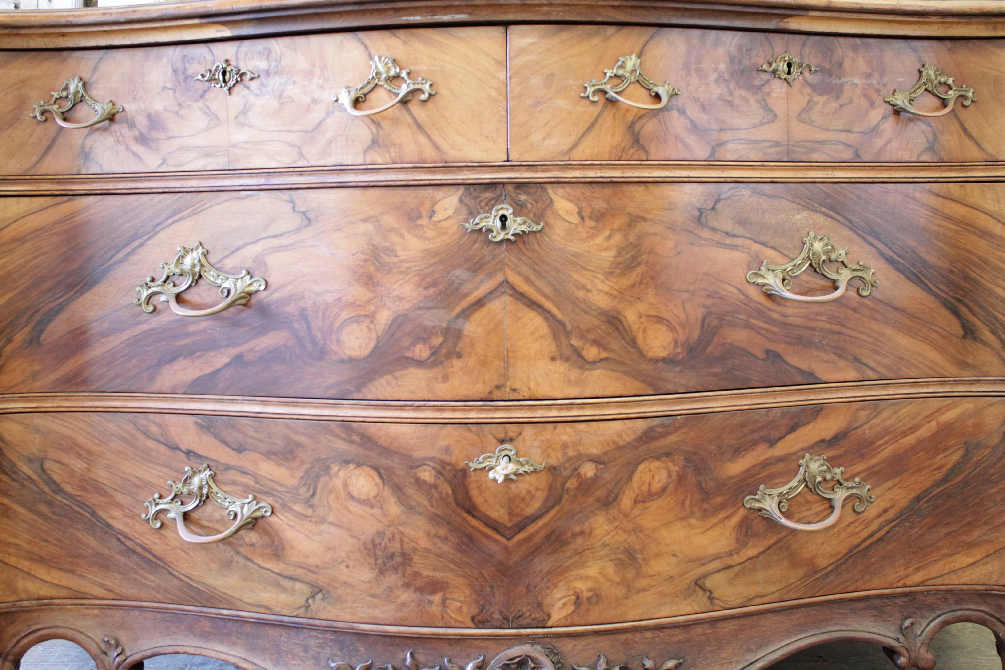 Exquisite chest of drawers commode hand-carved in the Louis XV style with large French cartouche and floral motifs. Rococo style commode made from solid mahogany, and English crotch bookmatch walnut veneers. Single key original to the piece is