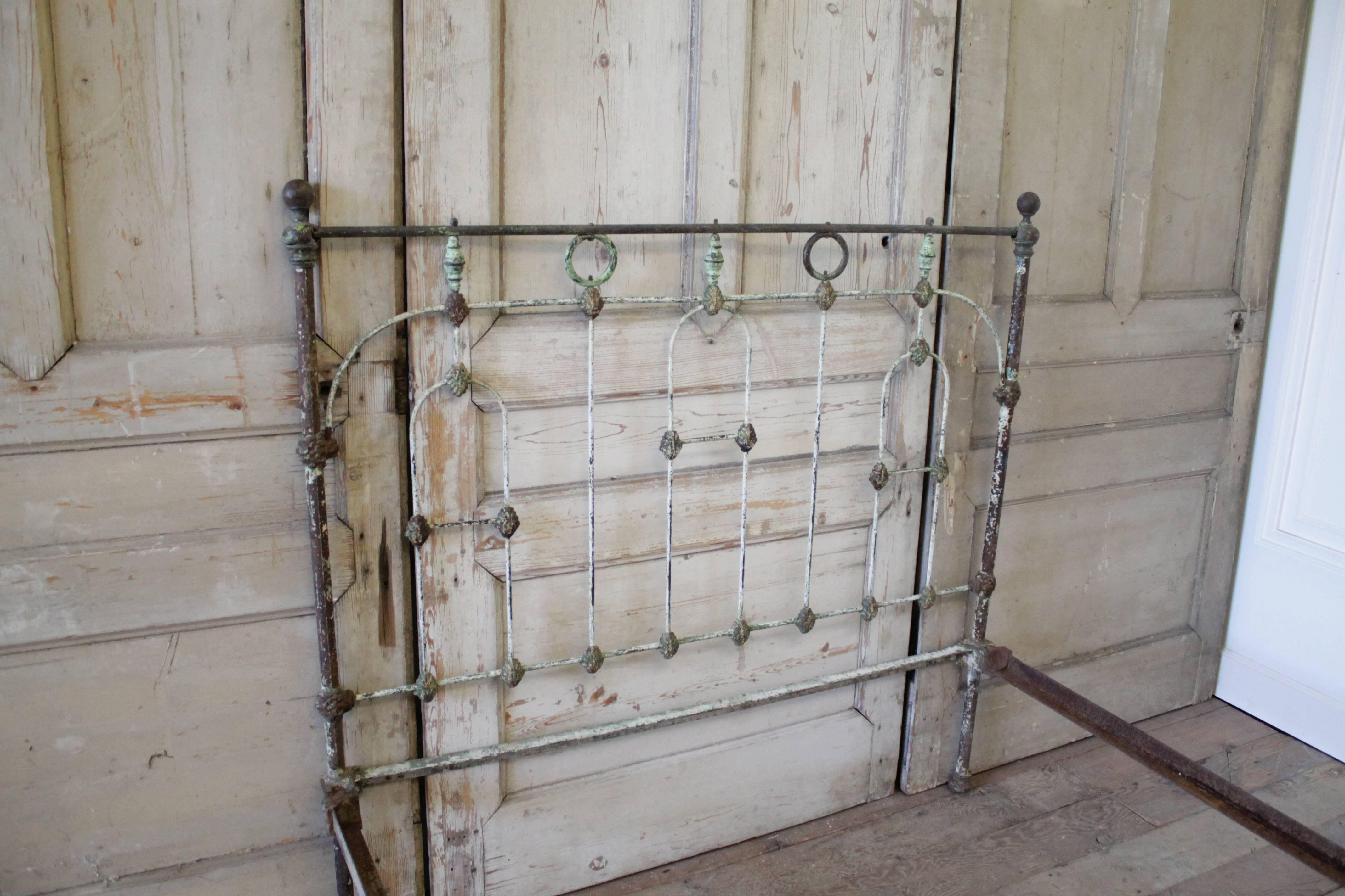 Solid iron bed accommodates a US full size mattress. Original patina with green and cream paint exposing the dark bronze colored iron and aged brass details.
Original side rails easily slide into the headboard and footboard, making it solid and