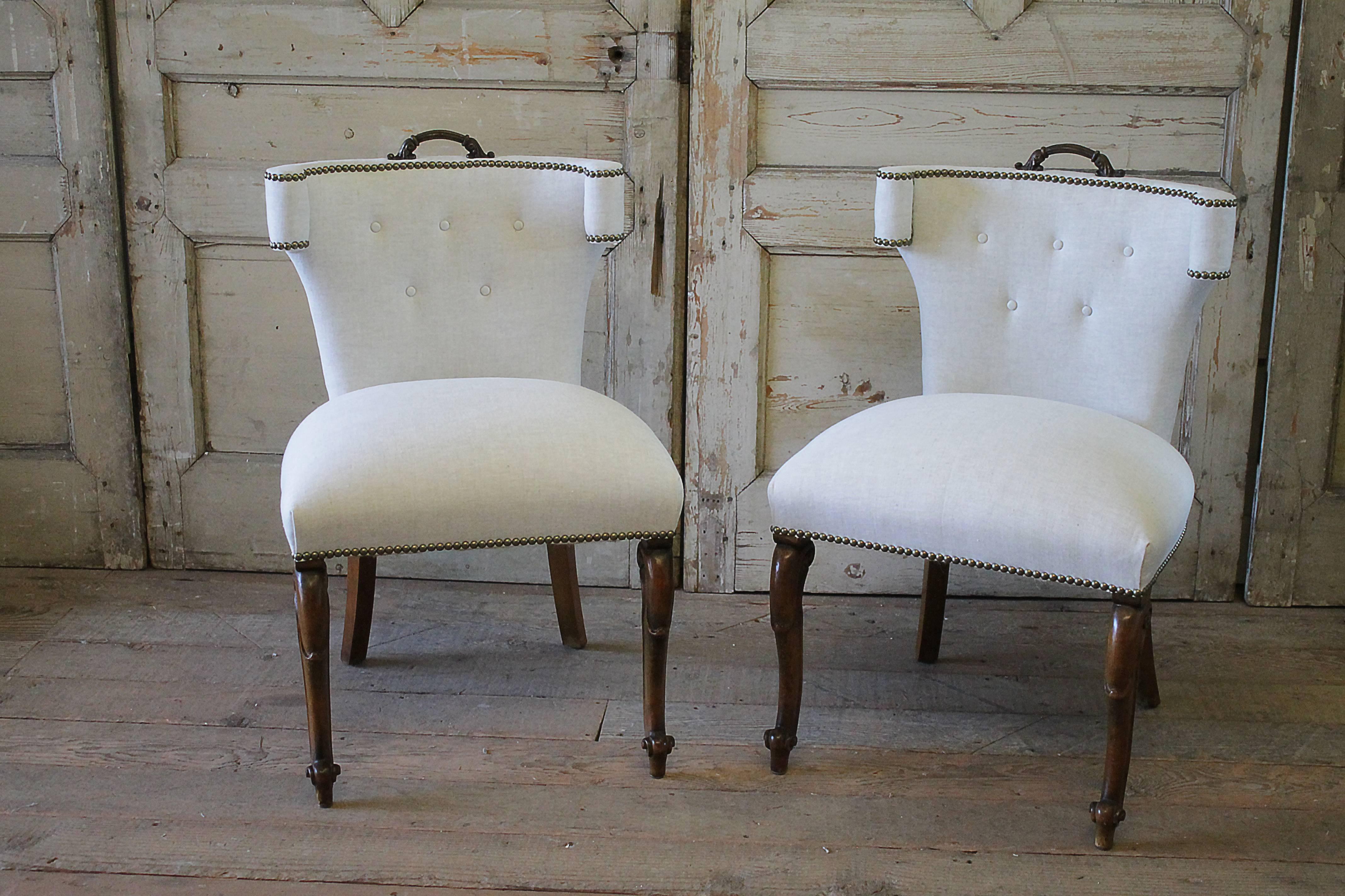 Fabulous set of four upholstered linen dining chairs from the early 20th century. These chairs came to us with an old cracked burgundy leather, and we have reupholstered them in a natural Belgian linen, and kept the original patina pulls atop the