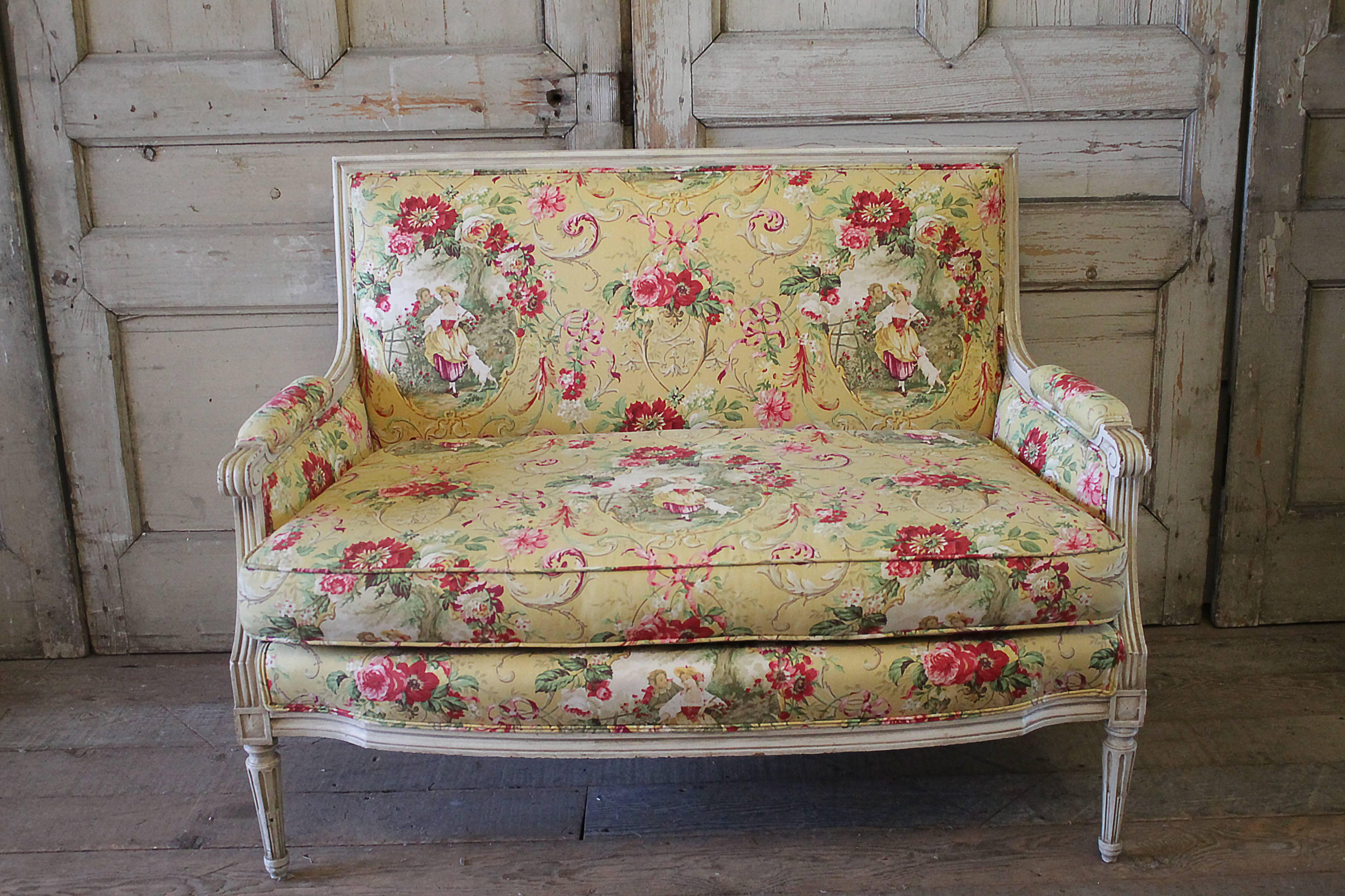 Beautiful Louis XVI style loveseat, with a creamy white painted frame. Subtle distressed edges, with an antique patina. Upholstered in a butter yellow toile de jouy cotton, with scrolls of dark pink and light pink floral clusters.
The seat is a