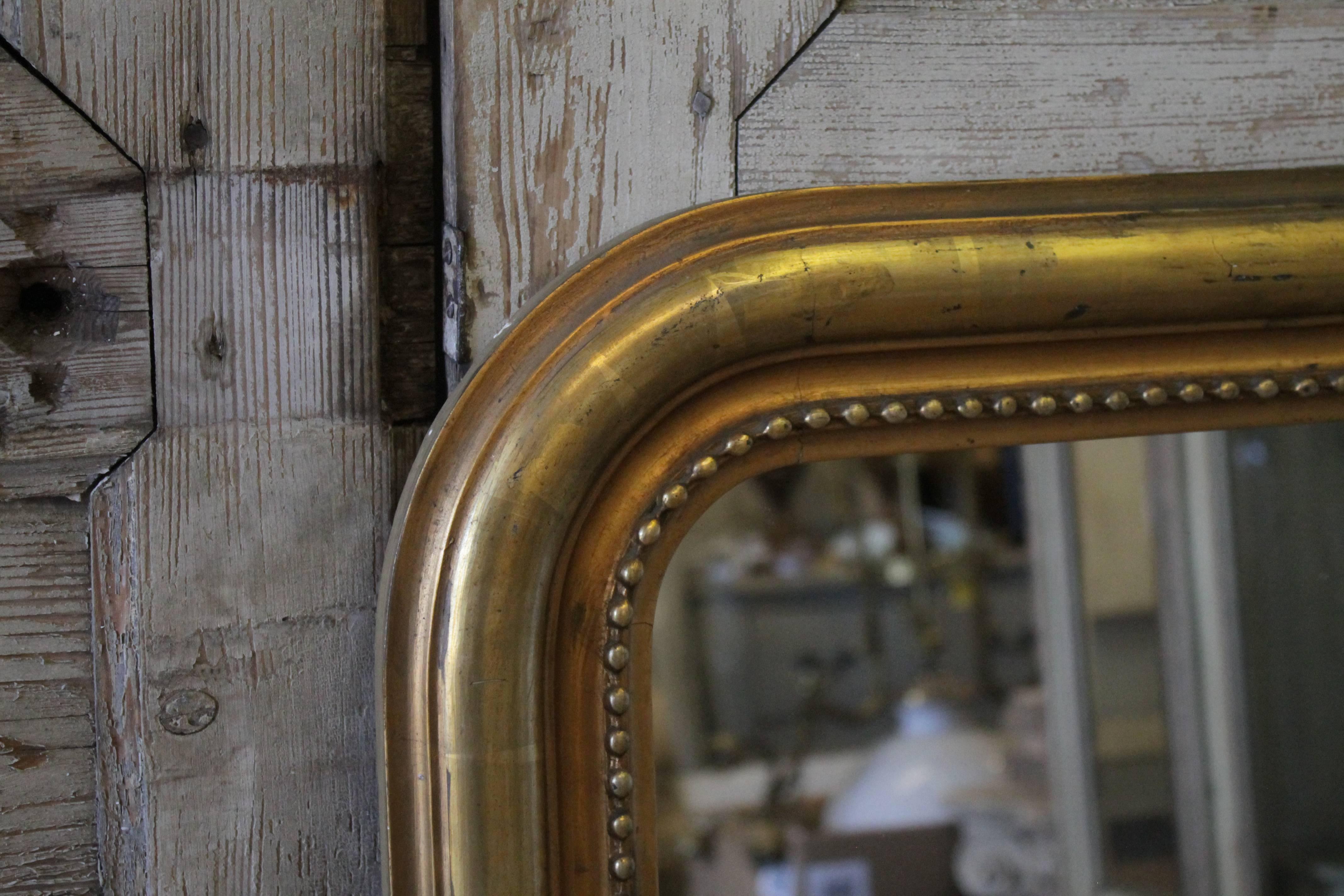 Lovely giltwood mirror has a nice bead-like motif around the edge of the inner side of the frame. Gilt has a lovely worn and faded patina. Back side is solid wood planks, with wire, ready to hang.
Measures: 25