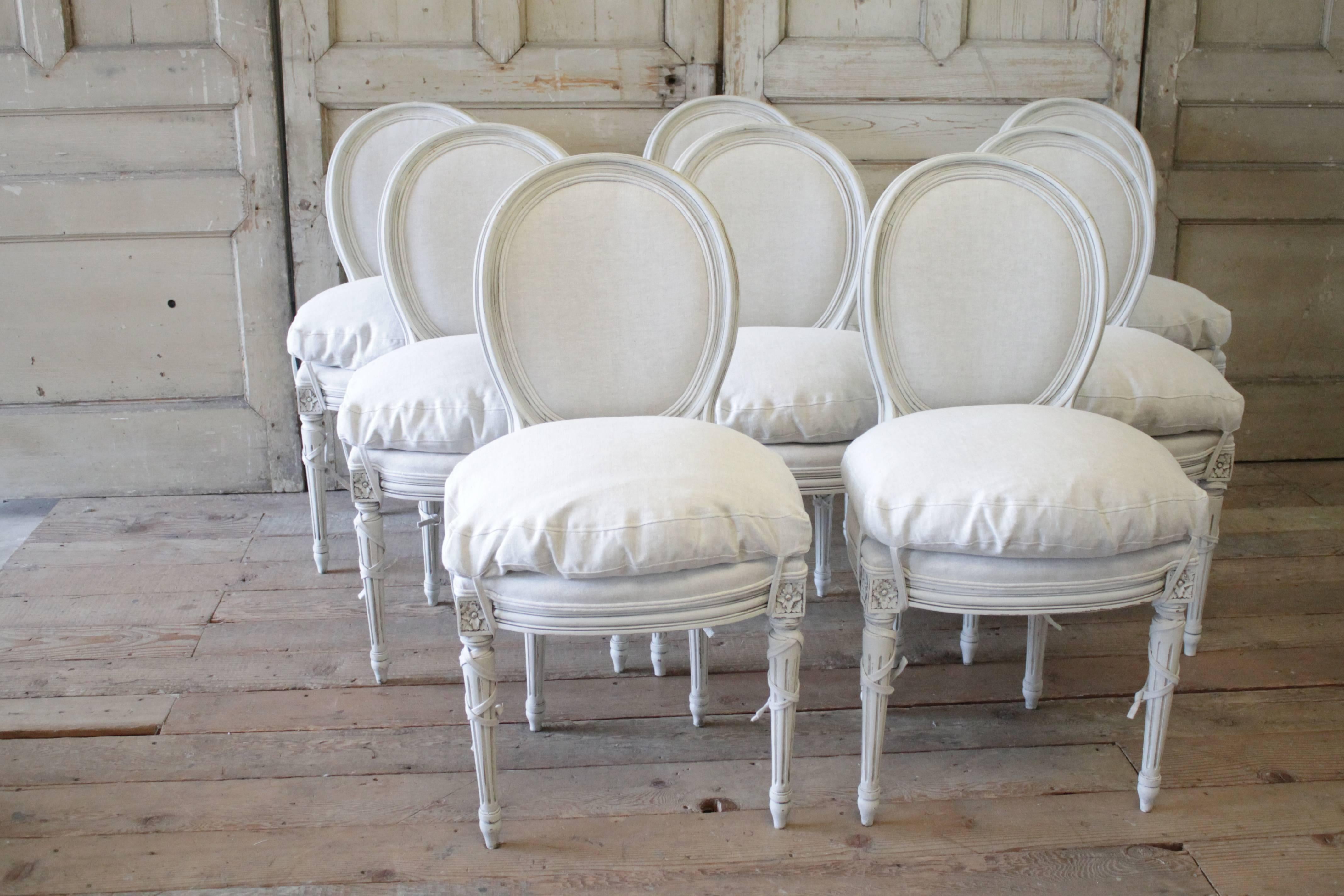 Lovely set of eight upholstered Louis XVI Style dining chairs. Painted in our signature oyster white finish, with subtle distressed edges, and upholstered in a greige (natural oatmeal) Belgian linen. The painted frame is a combination of off-white,