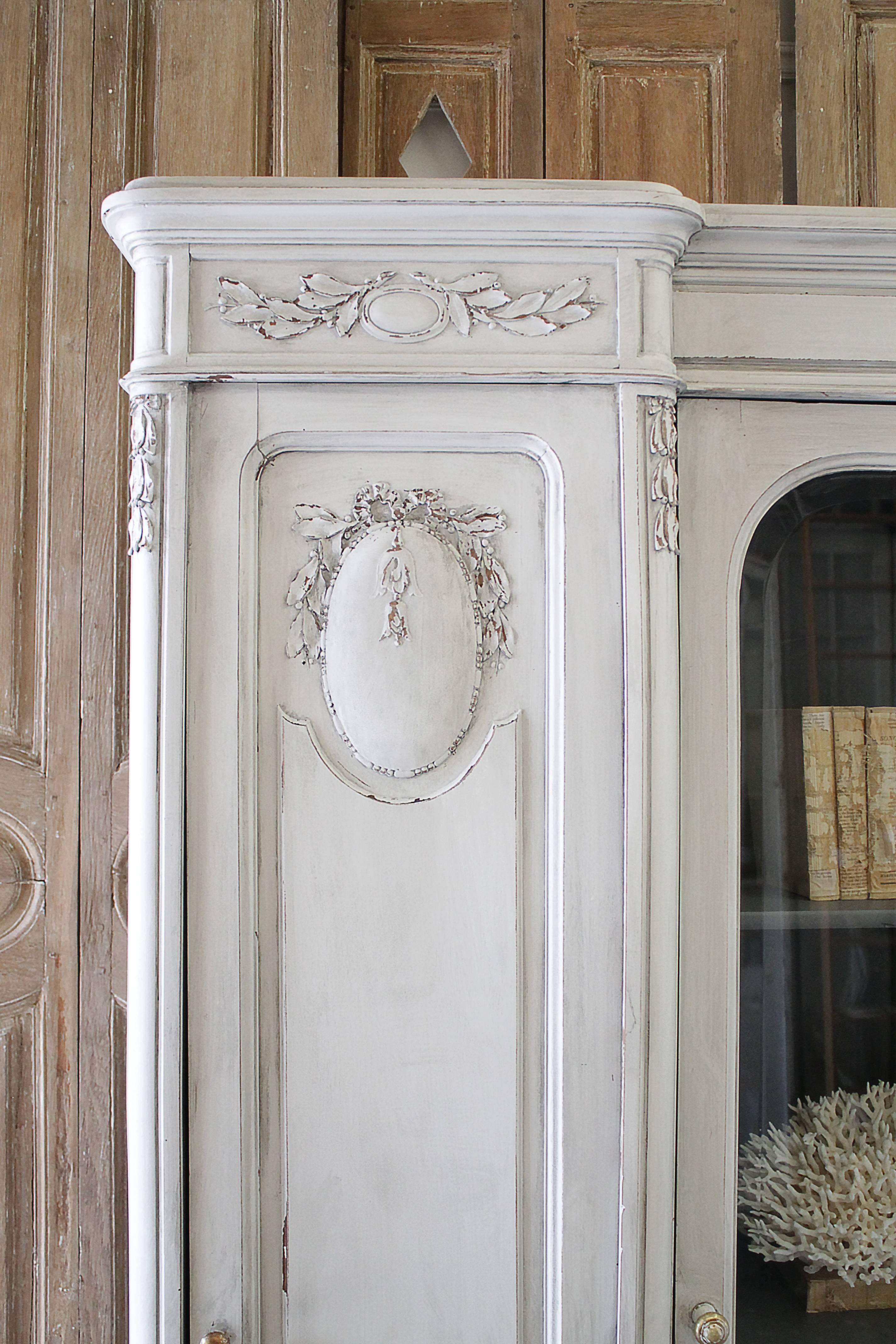 Beautiful early 20th century French style painted and carved display armoire. Three doors, the center door is a glass door to display, with adjustable shelves and one shelf has two drawers that open and close with ease.
The two side doors open up