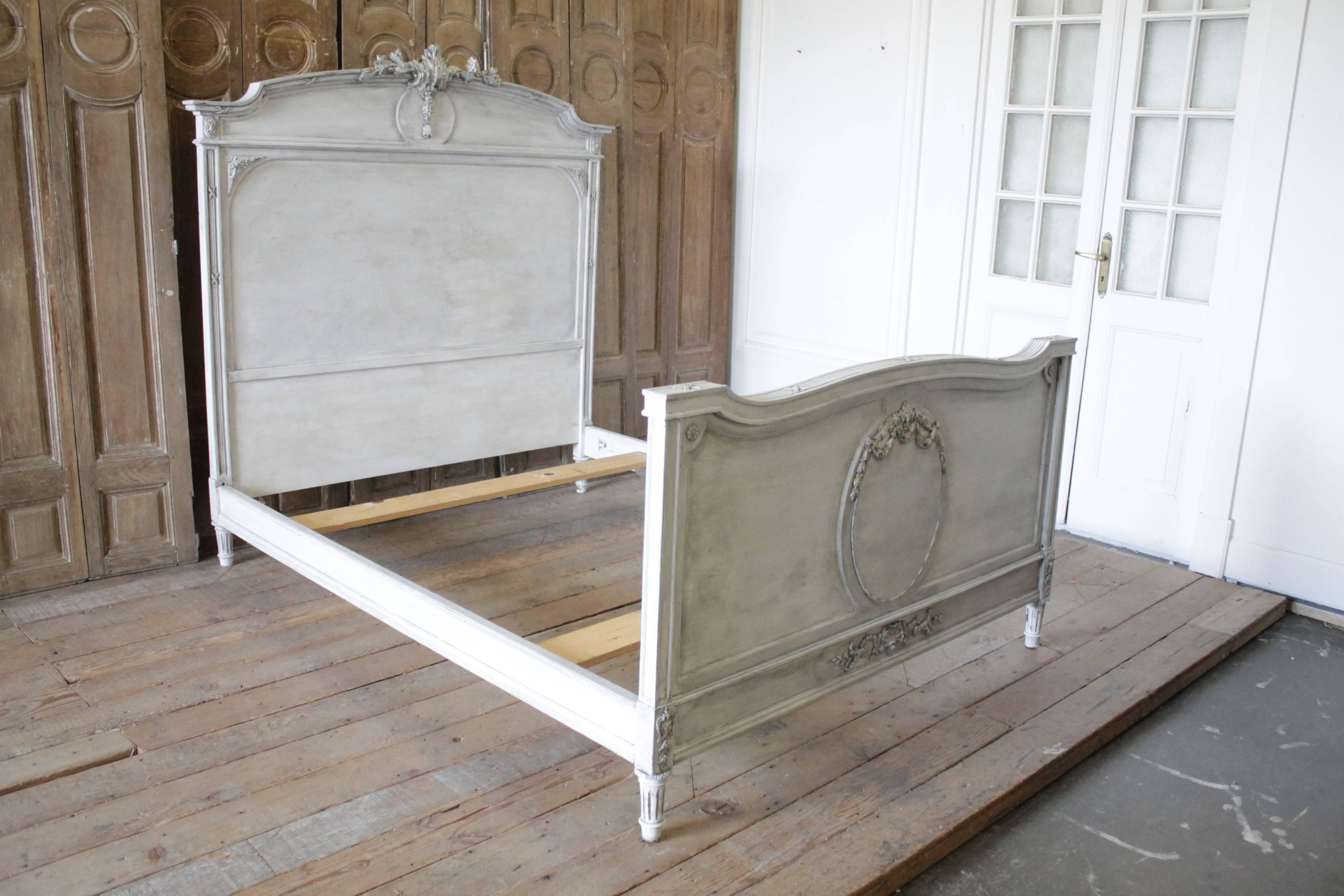 Beautiful French Louis XVI style bed painted in a soft off white, with subtle distressed edges, and hand applied patina to give the look of original painted finish. This bed frame fits a full size mattress. Includes headboard, footboard, original
