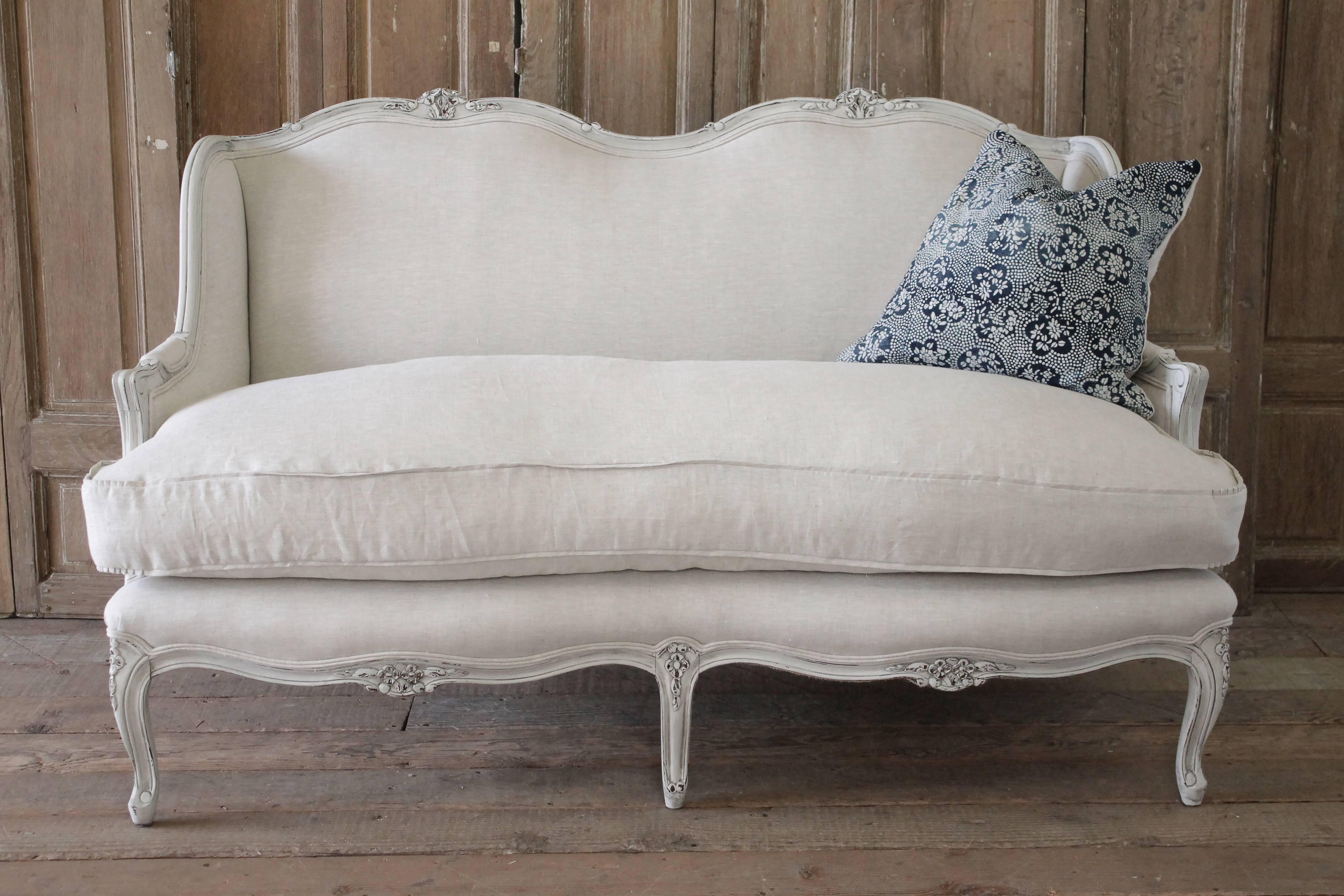 Lovely French Country loveseat painted in oyster white with subtle areas of distressing, and hand applied antique patina. Reupholstered in 100% pure Belgian linen, finished with a double welt edge, and new plump down cushion. Measures: 61