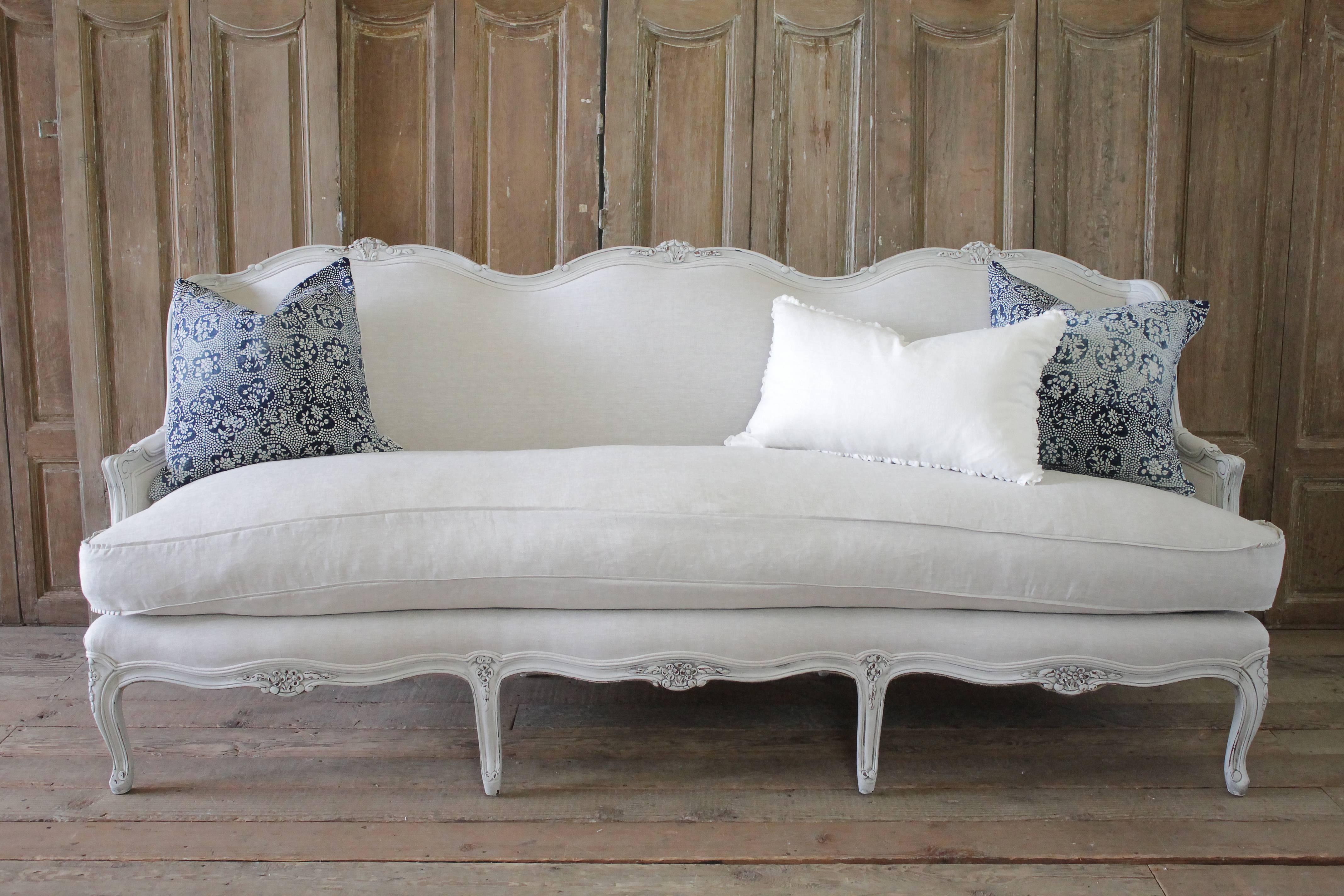 Lovely French country sofa painted in oyster white with subtle areas of distressing, and hand applied antique patina. Reupholstered in 100% pure Belgian linen, finished with a double welt edge, and new plump down cushion.
Measures: 84