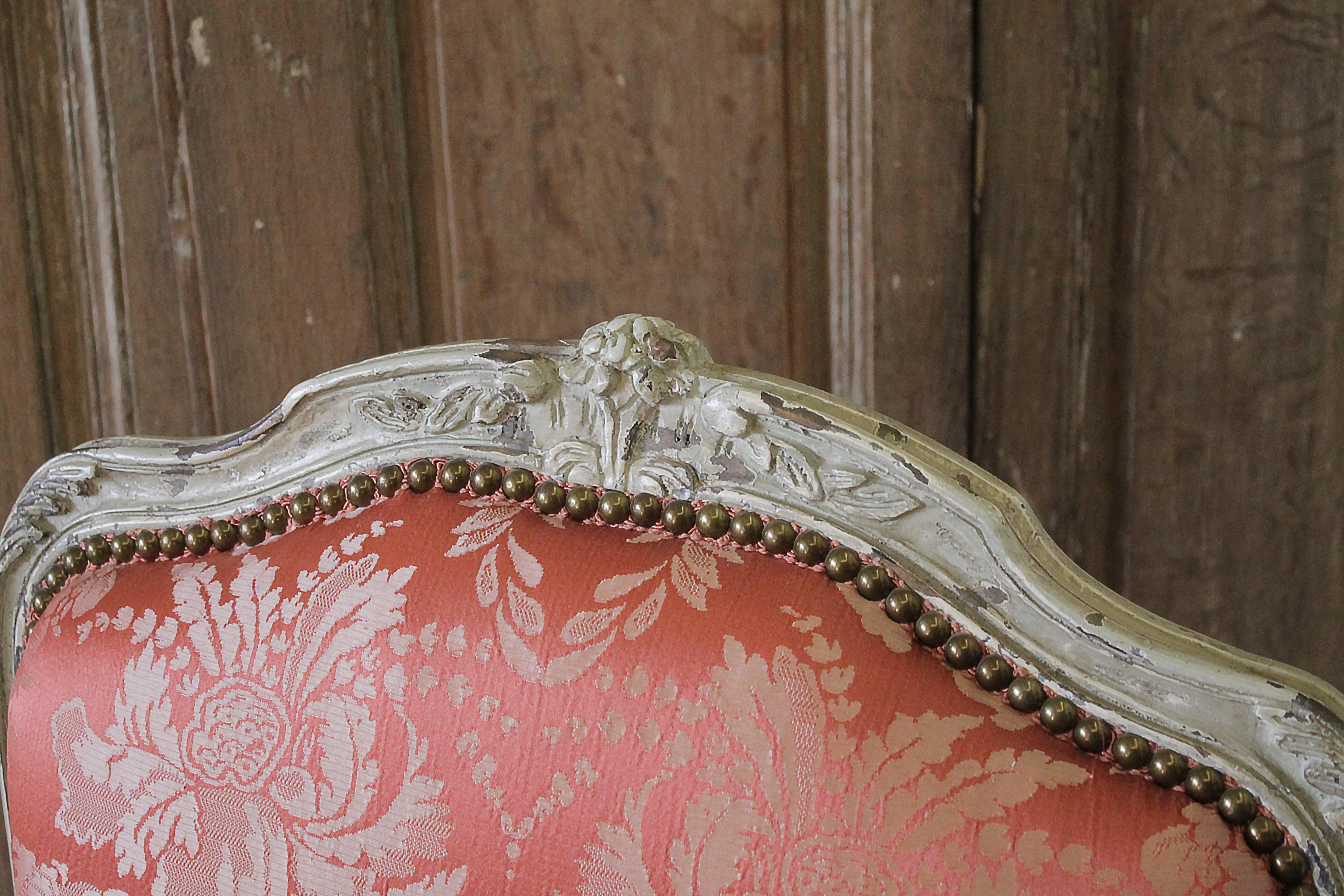 Gorgeous antique Louis XV Style original painted open arm chair, upholstered in Scalamandre silk fabric. The color is a rich deep salmon color with darker accent floral damask pattern. Seat is comfortable down cushion, finished with nail head