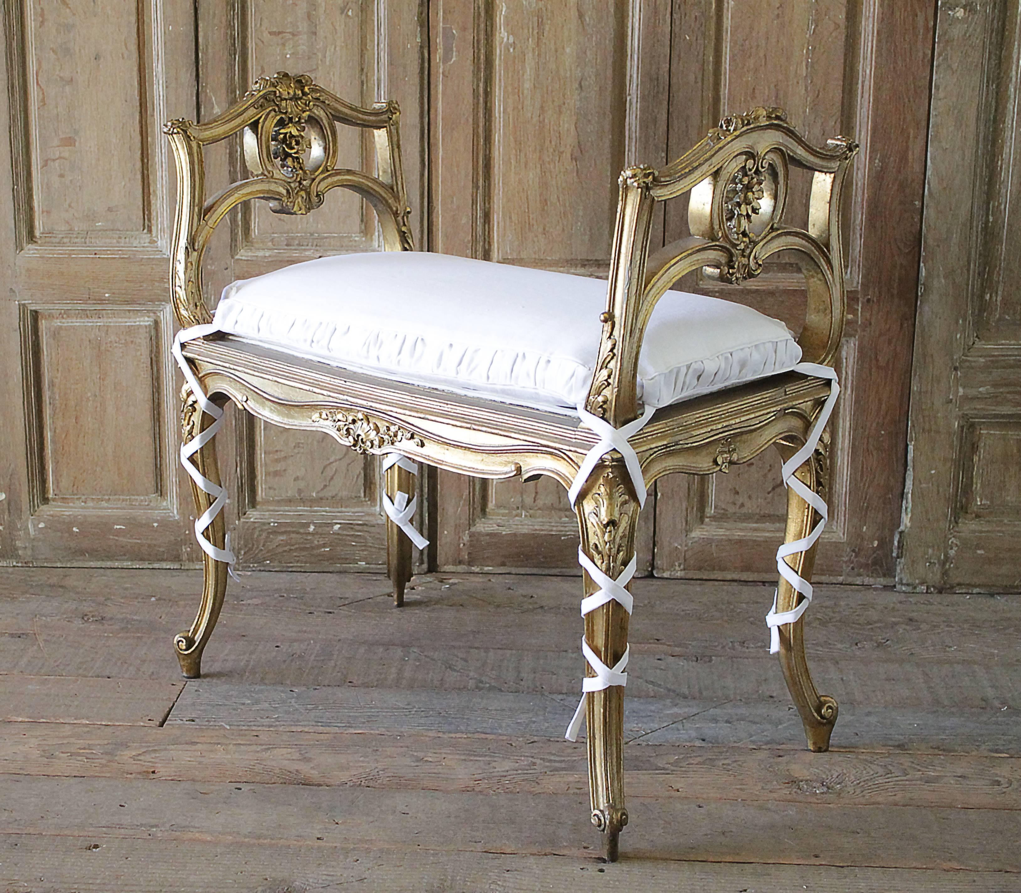 20th Century Carved Giltwood Bench with Linen Slip Covered Cushion
Original gilt finish, with subtle areas of patina, Louis XV style carved legs, and rococo carved sides, with floral motifs.
We added a custom made slip covered cushion with rusched