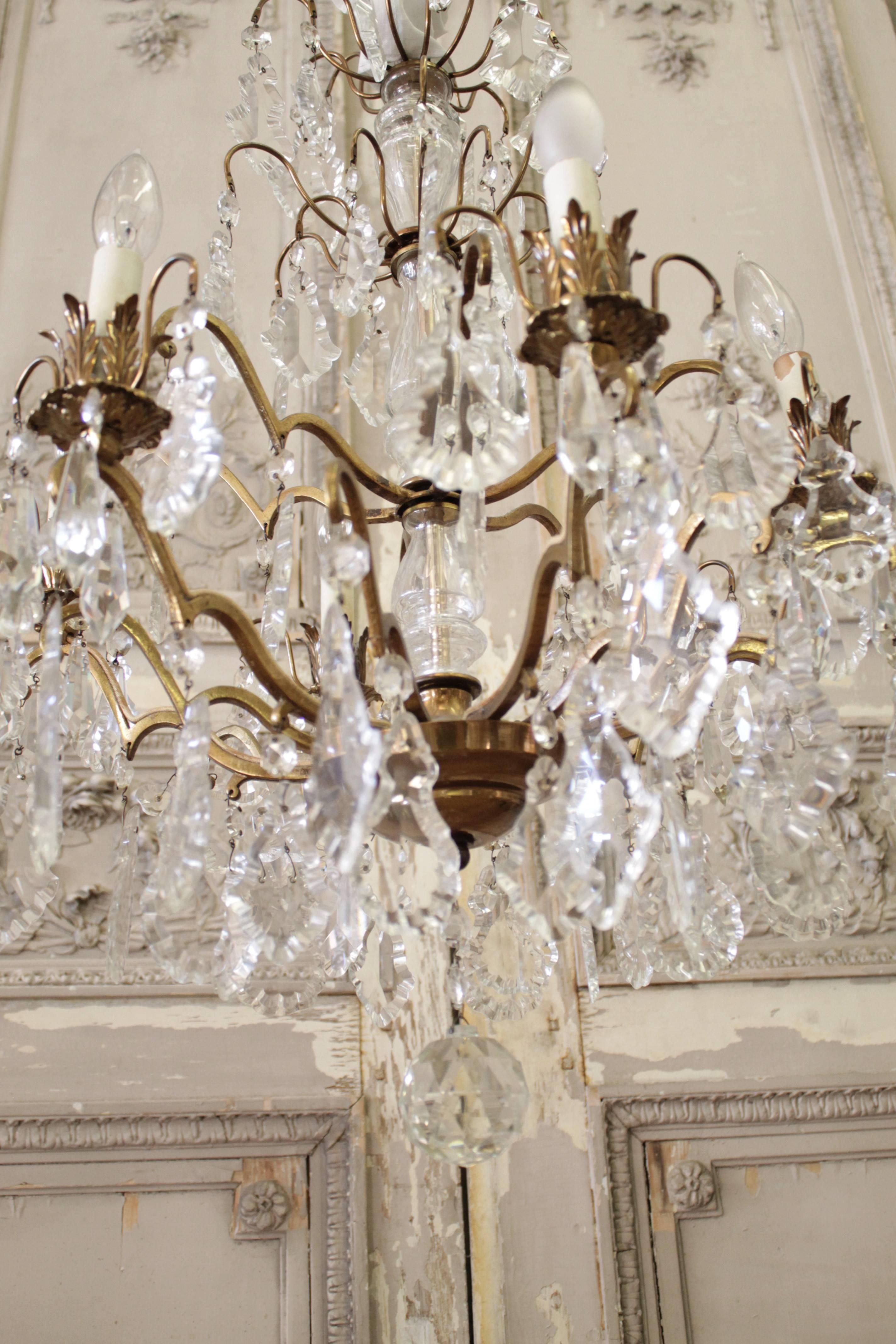 This elegant crystal chandelier is beautifully detailed. Its six arms are heavily draped with French pendant shaped crystals. This piece is finished on the bottom with a large fiery faceted crystal ball.
This uses US standard electrical chandelier