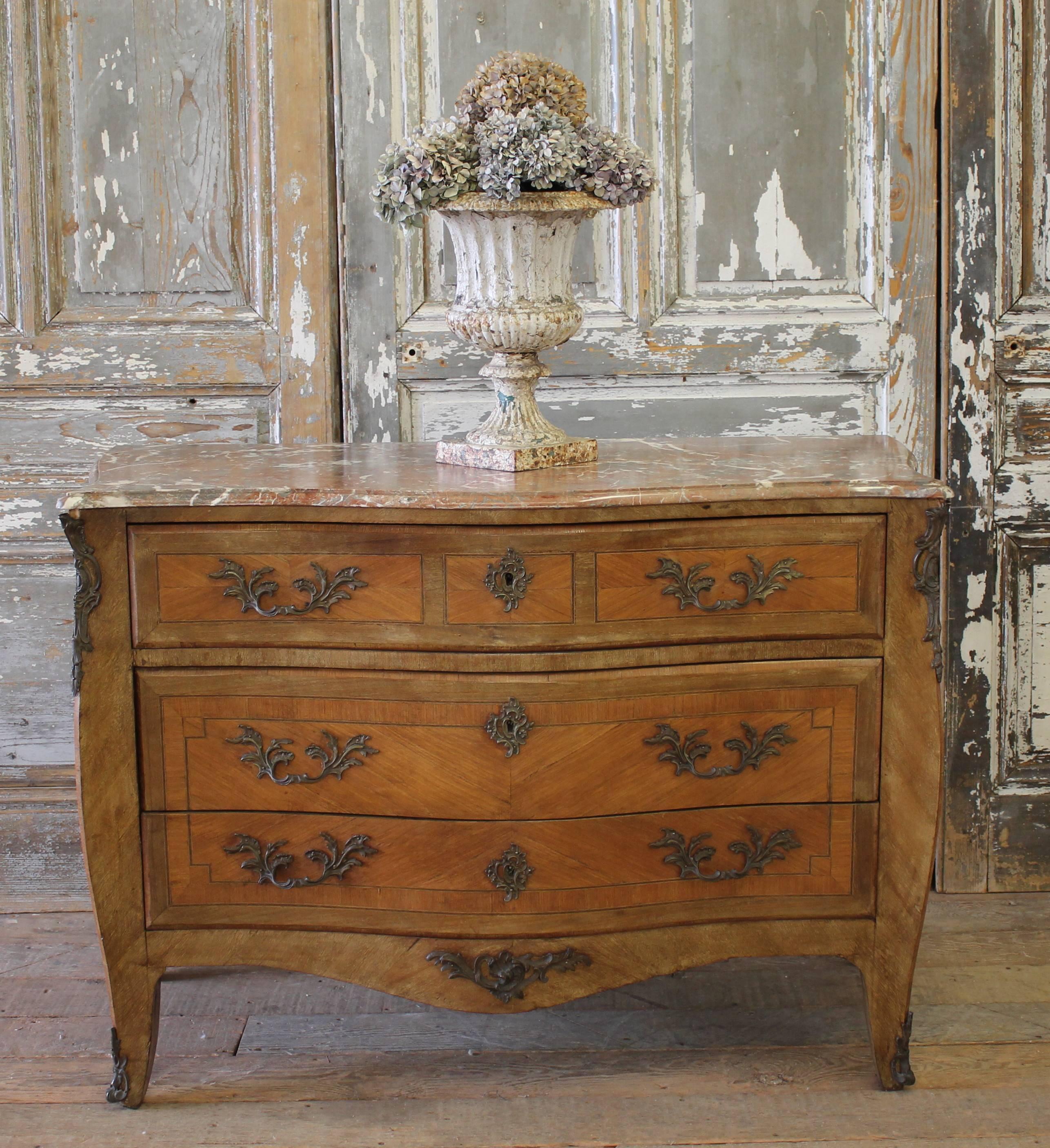 This is a beautiful antique marquetry inlaid serpentine commode, circa 1880. This gorgeous commode has three spacious drawers for ample storage and was inspired by the Louis XV style. 
Kingwood and mahogany, ormolu-mounted bombe commode with a