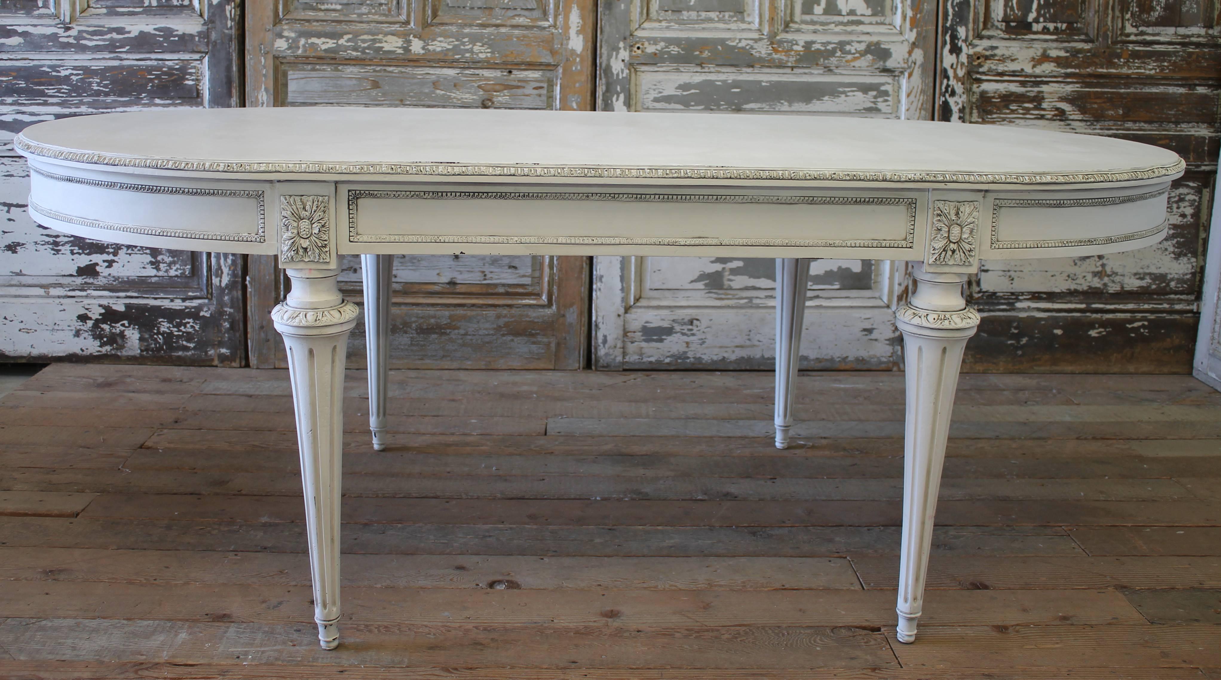 This beautiful table is painted in our signature oyster white finish, with hand rubbed glazed patina. The carvings around the edge of the table top are bronze, as well as the apron, floret and rings at the top of the legs. The table top has patina,