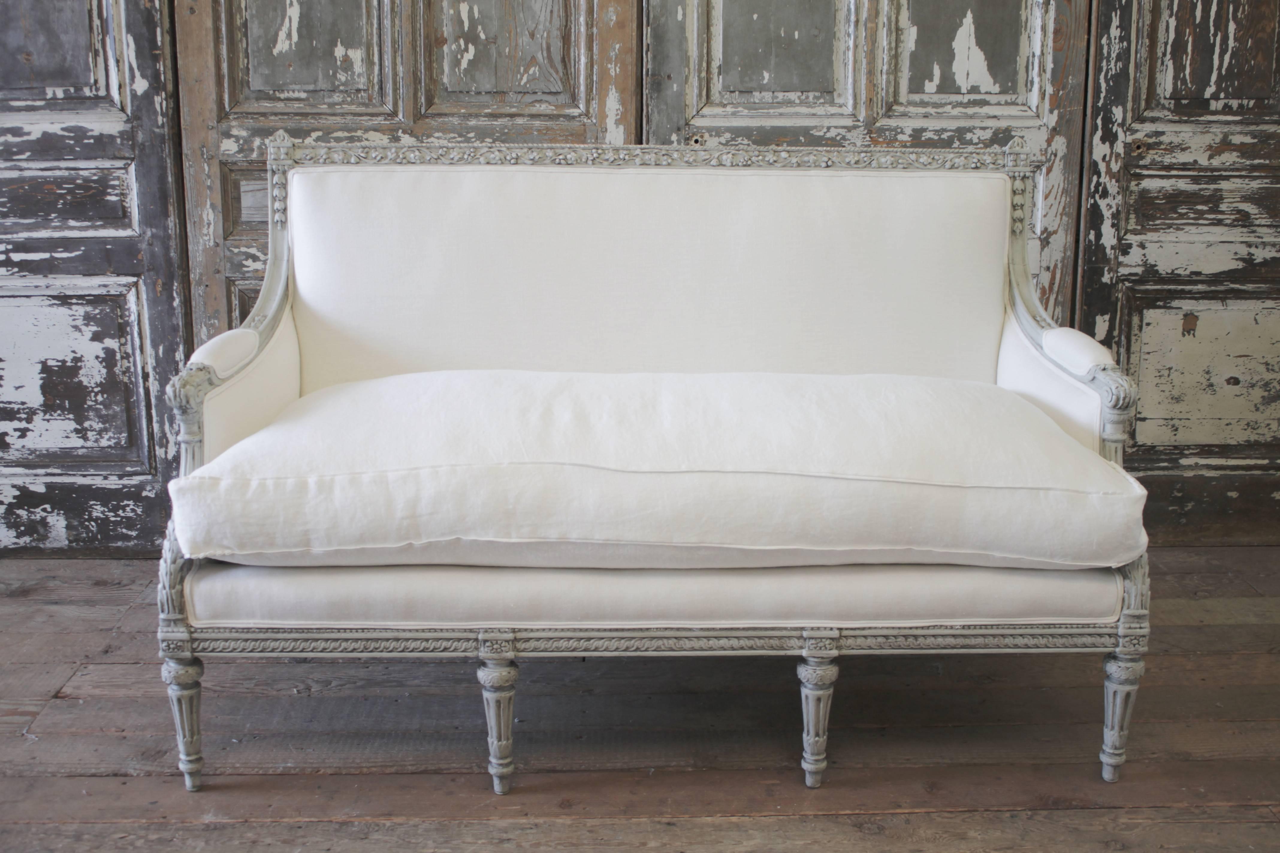 Beautiful French carved sofa in the Classic Louis XVI style.
We painted this frame in a soft clam shell grey, hand applied faux glaze and waxed finish. You can see a little gilt and creamy color paint peeking through. Gorgeous acanthus leaf
