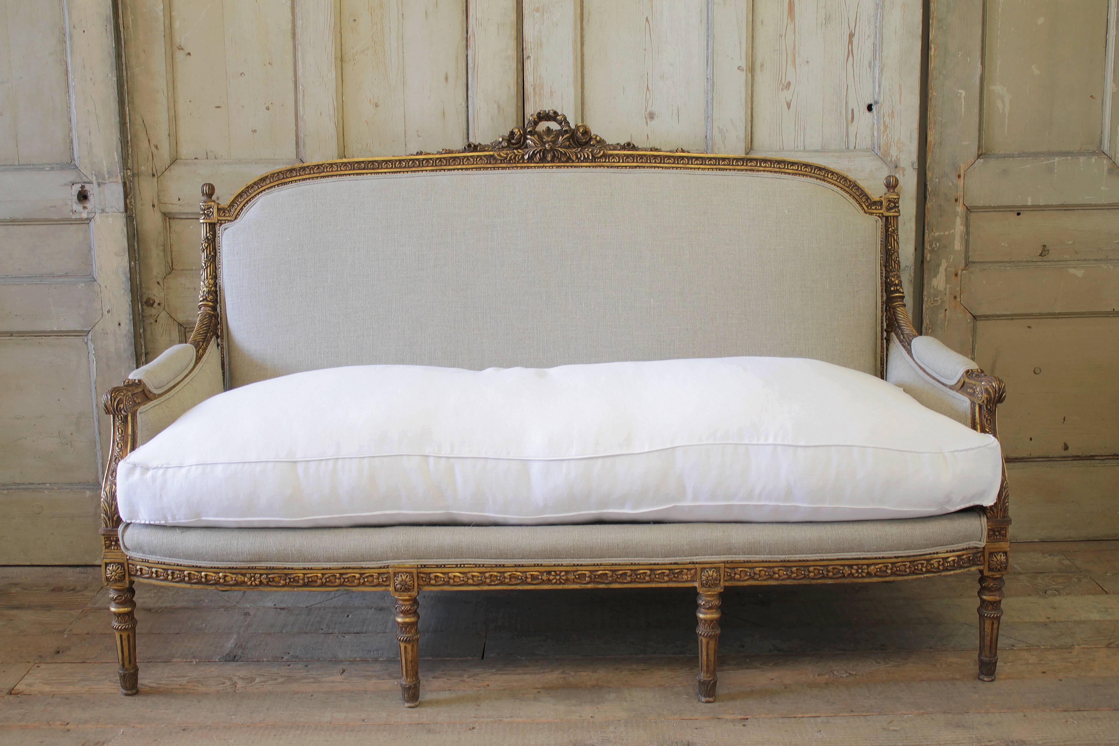 Fabulous French sofa in the Louis XVI style. This sofa is one of our favorites, it has a large carved rose wreath, with intricate carved details along the frame. There are carved finials, with a floret and carved roses trailing around the fluted