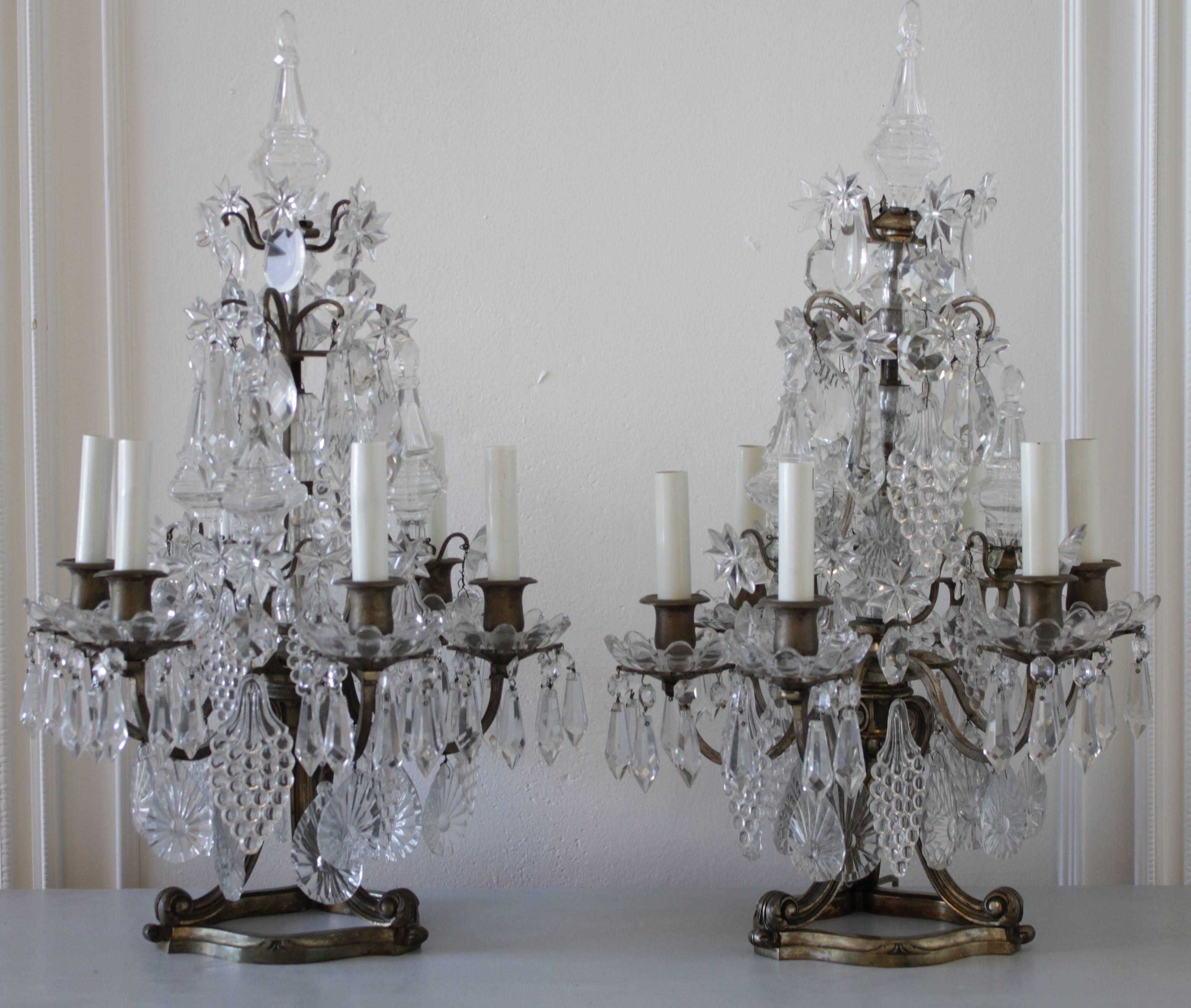 Gorgeous pair of dripping crystal candelabra. These are loaded with very unusual shaped grape crystals, tear drop crystals with sunbursts and spheres. Large obelisks, and star-shaped florets, drape down to the beautiful glass cupped bobeches. Each