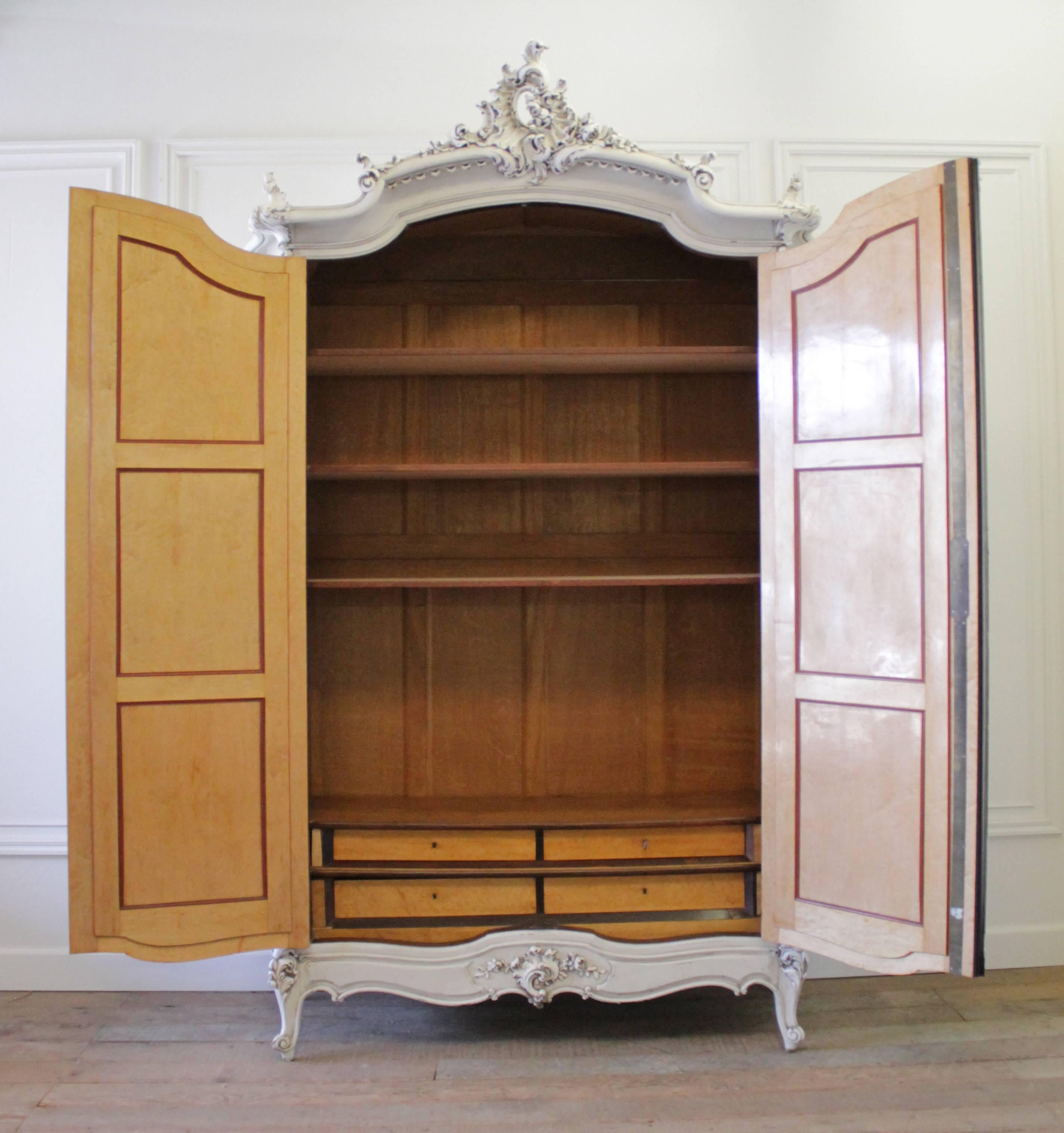 Impressive Louis XV armoire in rosewood and bird's-eye maple. Incredible carved cartouche in the Rococo style. A massive crest with roses, scrolls and clam shell edge, we painted the outside of this armoire to soften the look and show all of the