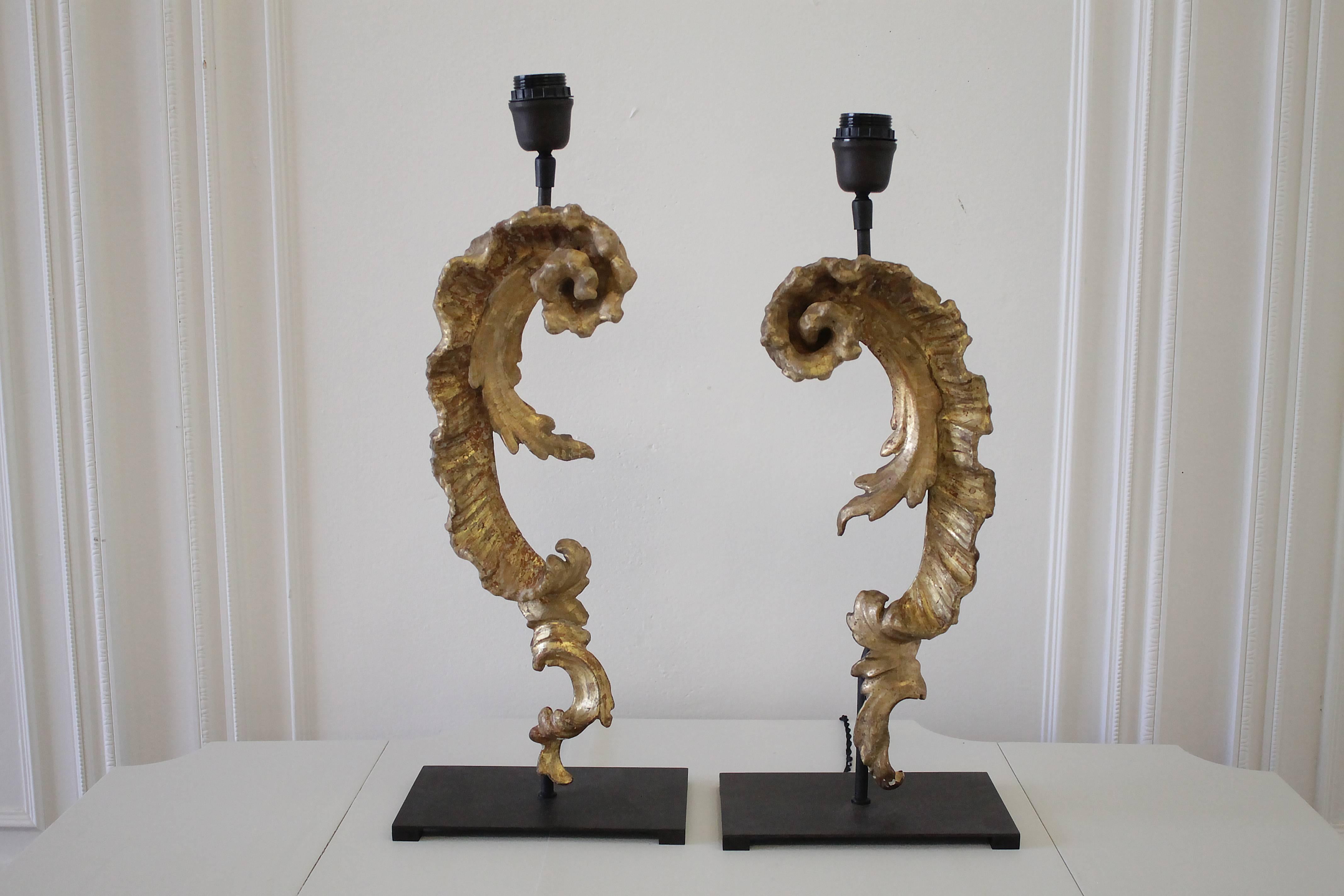 Beautiful pair of French scroll fragment lamps, mounted on dark metal bases.
Delicate gilded scrolls, each carved similar but still unique. 
Lamp #1 measures 21.25