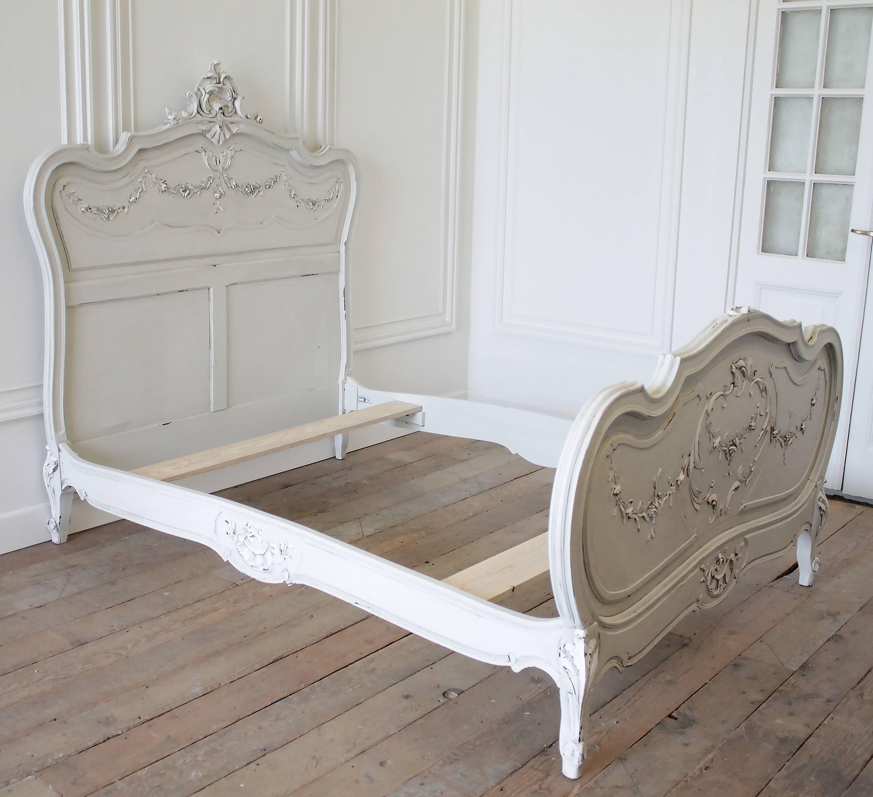 Classic Louis XV style Rococo bed has been painted in our oyster white, with soft white detailing. Finished with a slight distress, and antique glaze to give a time worn patina. The headboard has a large carved cartouche with large carved rose's