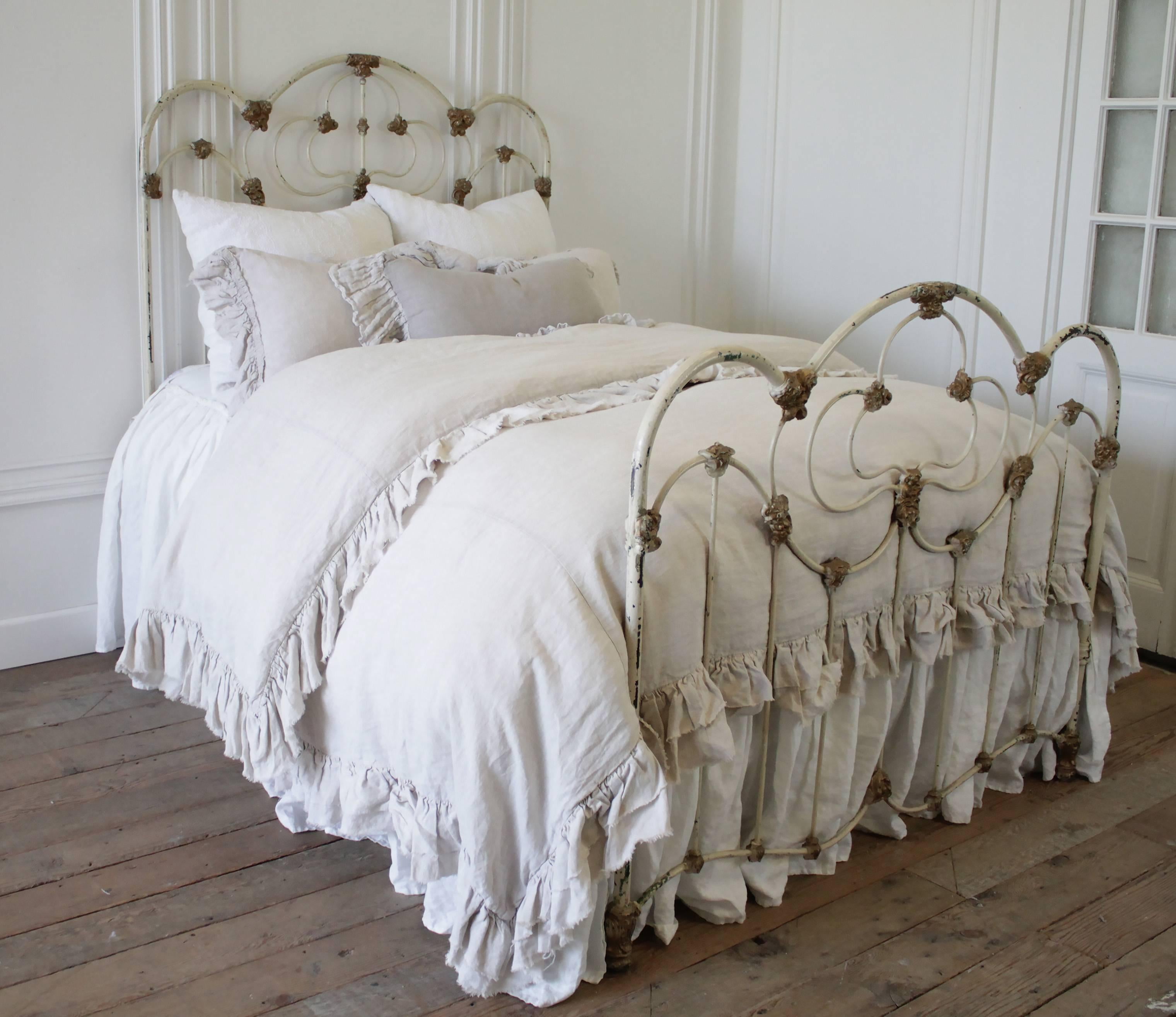 Beautiful French country antique iron bed painted in a soft creamy white finish, and gold accents. Solid iron, this bed fits a full size mattress. Layers of paint, chipping to reveal colors that once adorned this bed, creating a fabulous patina that