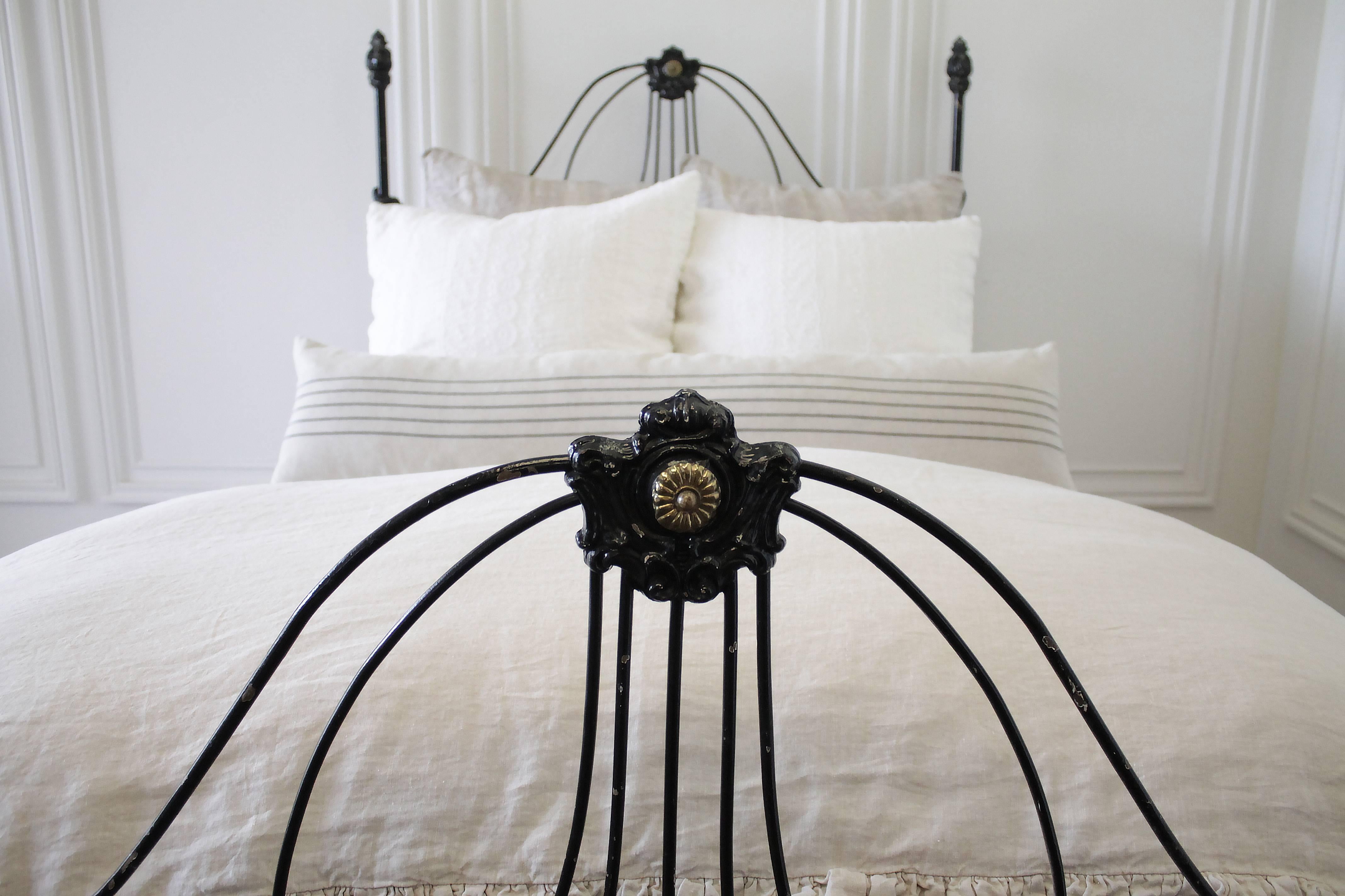Beautiful antique iron bed from the mid-1800s in a distressed black painted finish. The paint is not the original, and looks to have been repainted over the years. A beautiful time worn patina. The center headboard and footboard medallions have a