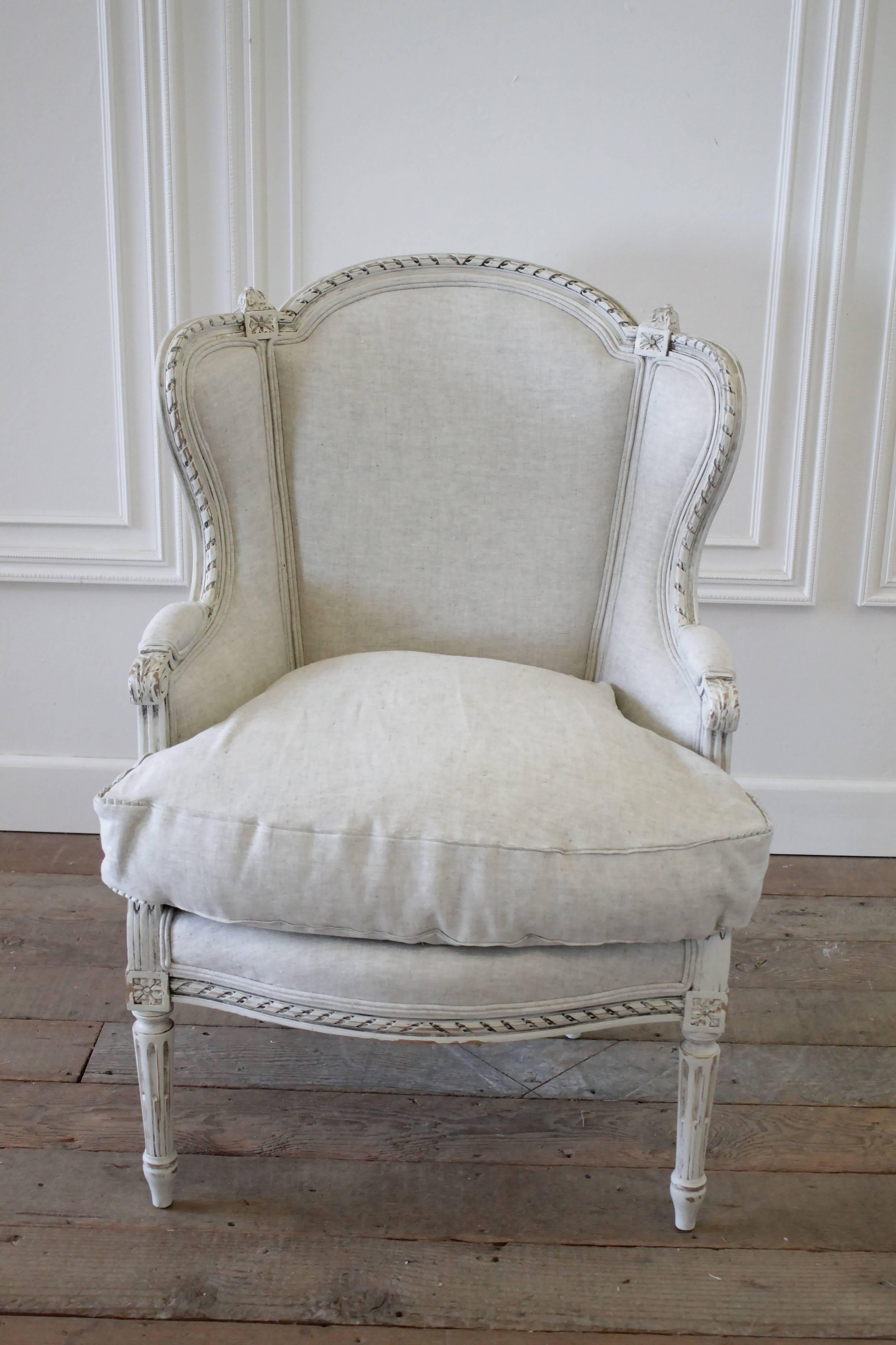 Beautiful French Louis XVI style wing chair has been painted in our oyster white, with subtle distressing, and an antique hand glazed finish. The paint colors are of an off white, with tones of grey and brown. The upholstery is done in a heavy