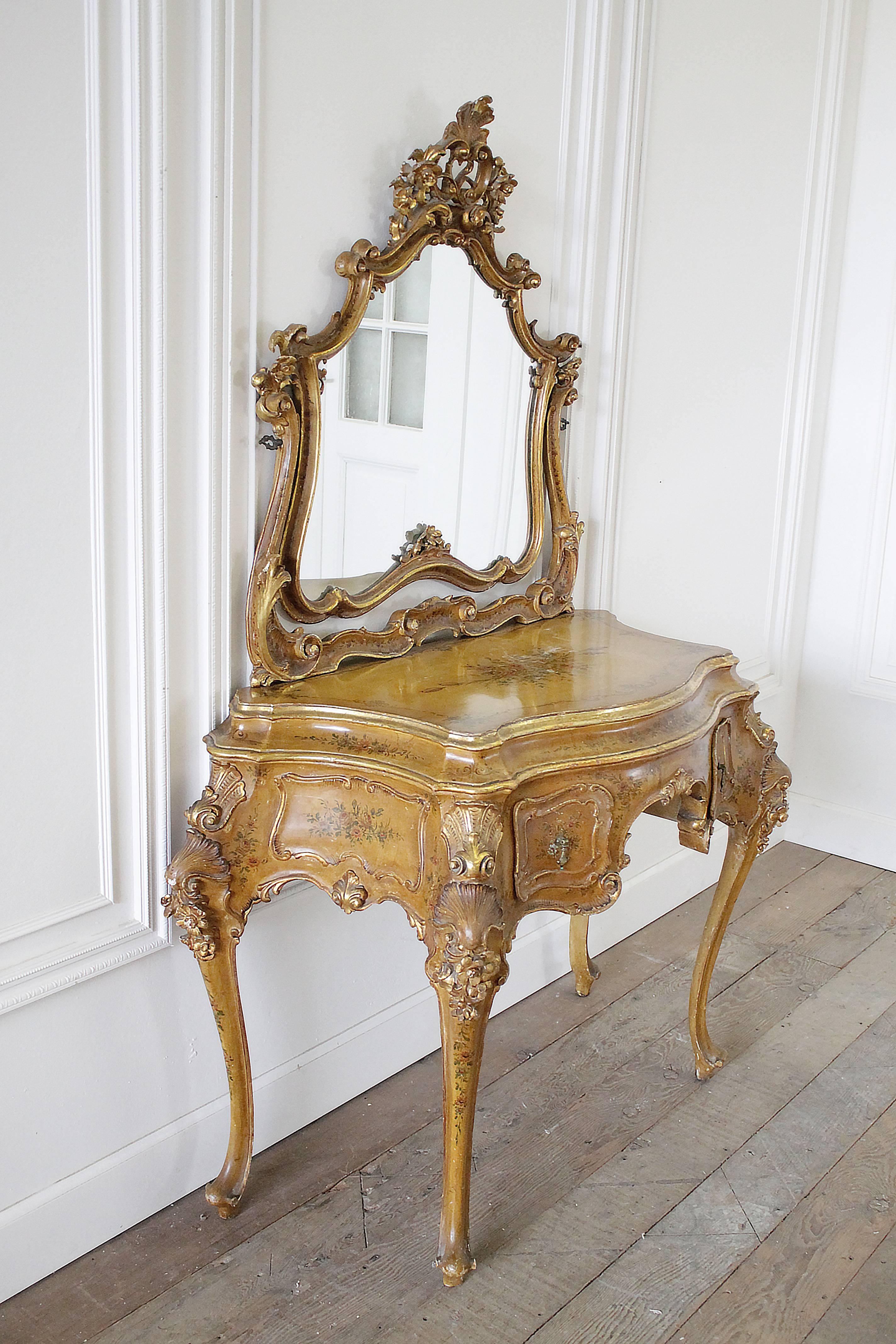 Gorgeous Italian vanity has the original finish in a dark mustard tone, with hand-painted bouquets of flowers. There are two working small drawers and mirror, that looks to be original. The carvings are exquisite, with shells, and flowers, and