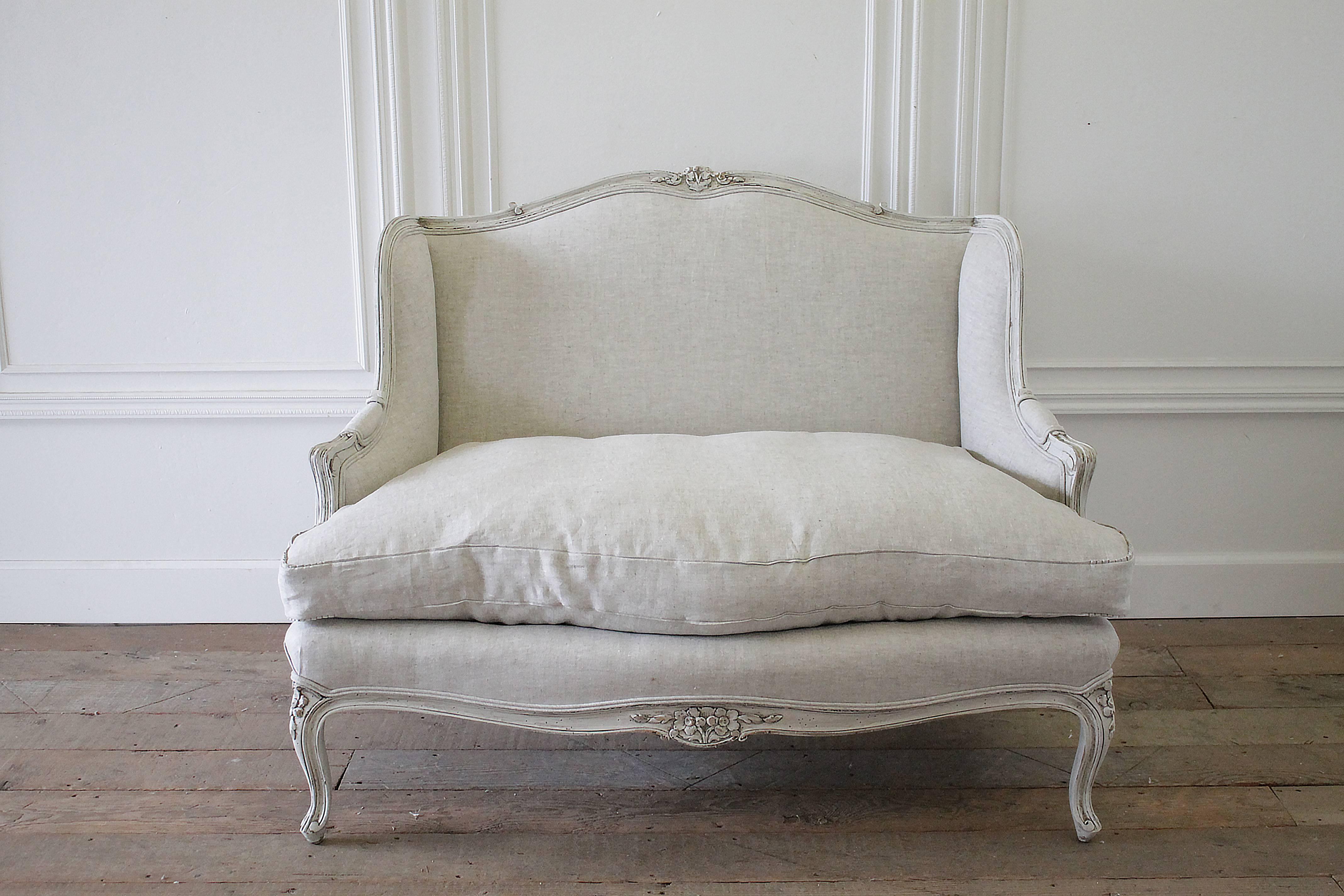 Fabulous country French Provincial settee has been painted in a soft oyster white with subtle distressing and a hand glazed and waxed finish. Louis XV style legs, and carved flowers, add a romantic touch. The settee has been reupholstered in our