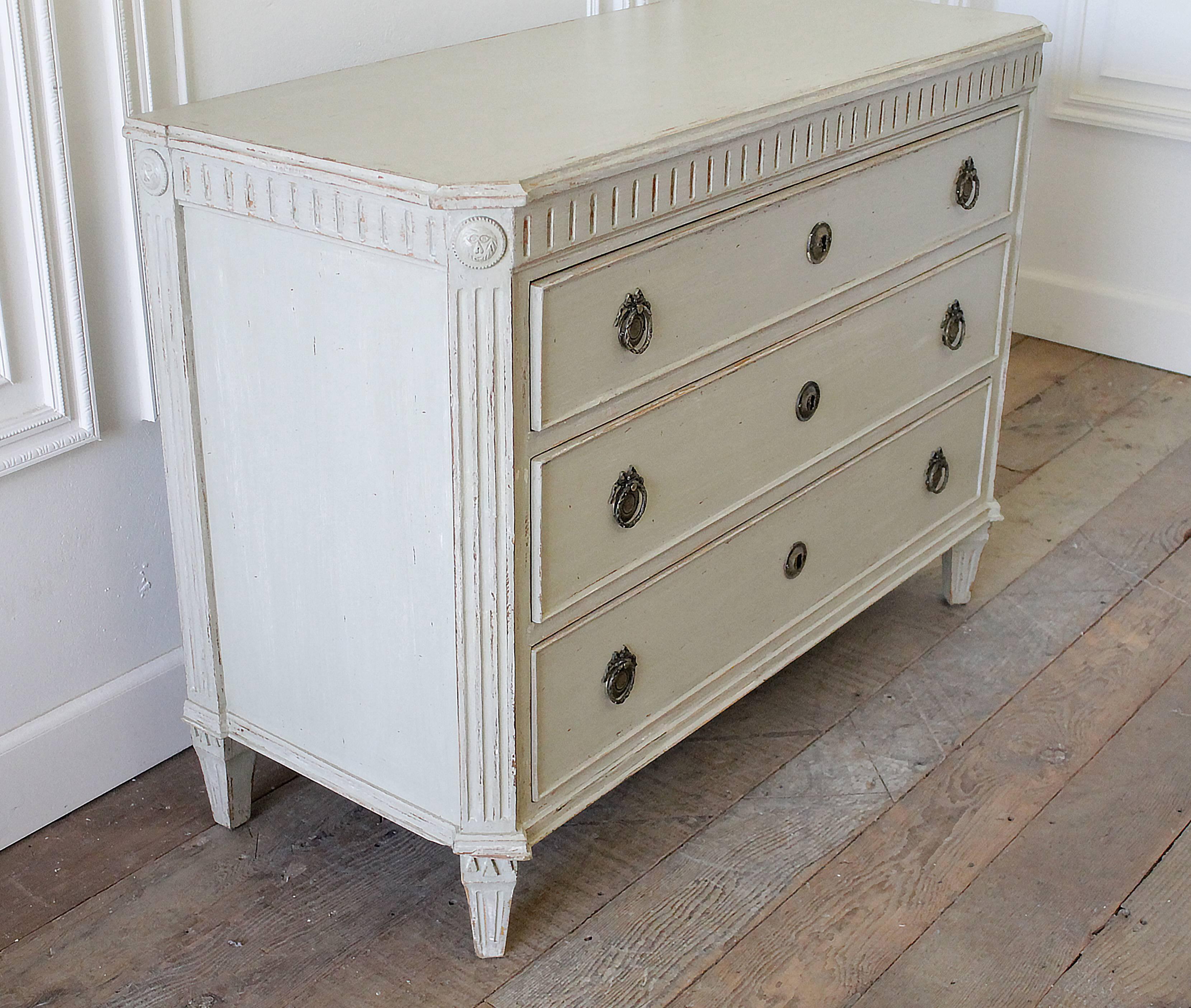 Gustavian Style chest of drawers with fluting above upper drawer. Shaped top with canted corners and classical feet. Very classical Swedish piece with original charming hardwares, decorated with ribbons. Painted in a grey with subtle green