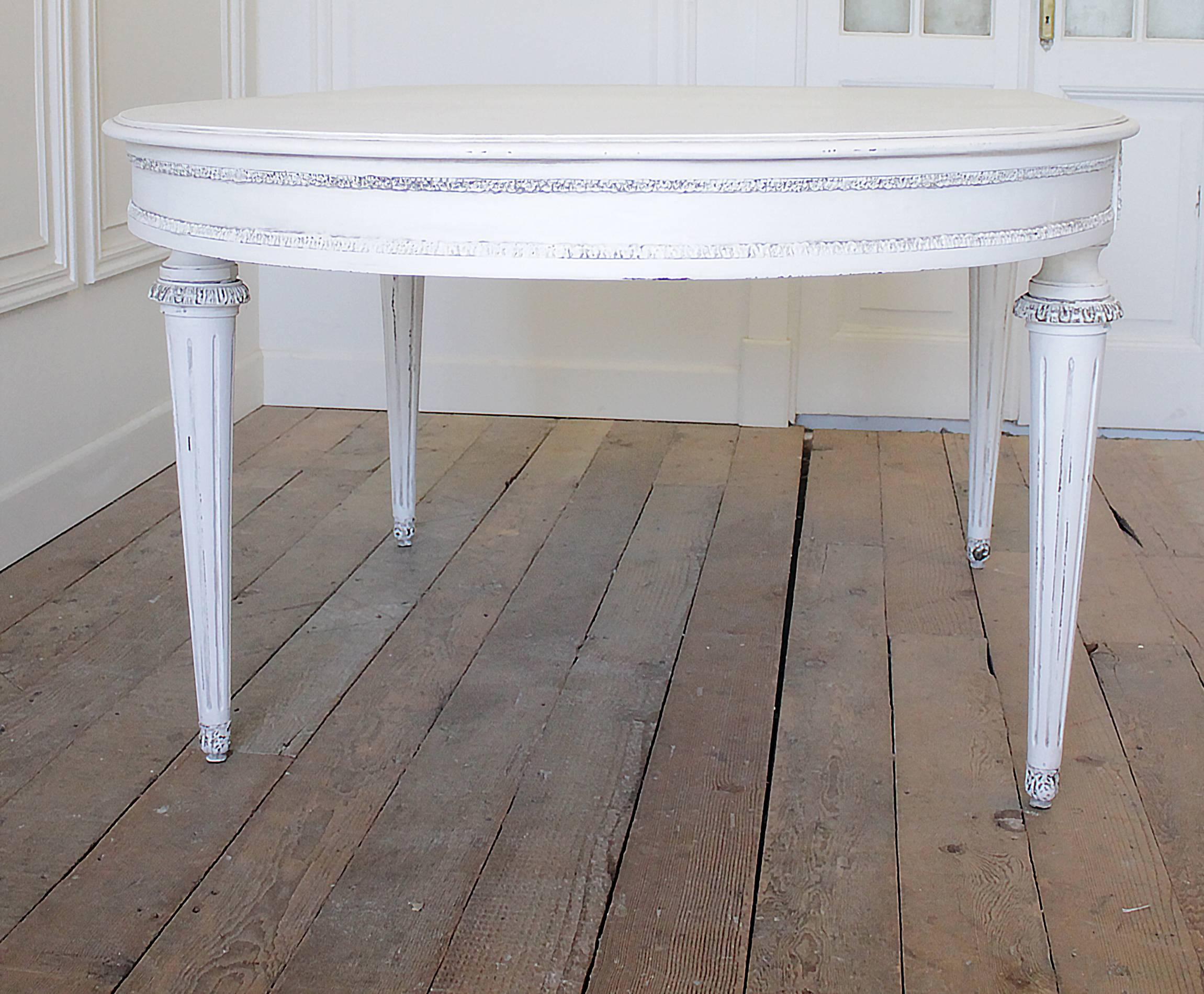 Large mahogany painted table in a soft oyster white, with subtle distressing and finished with an antique glaze. Classic fluted legs, with bronze-mounted decorations and trim. Legs are sturdy ready for everyday use. 
Measures: 89