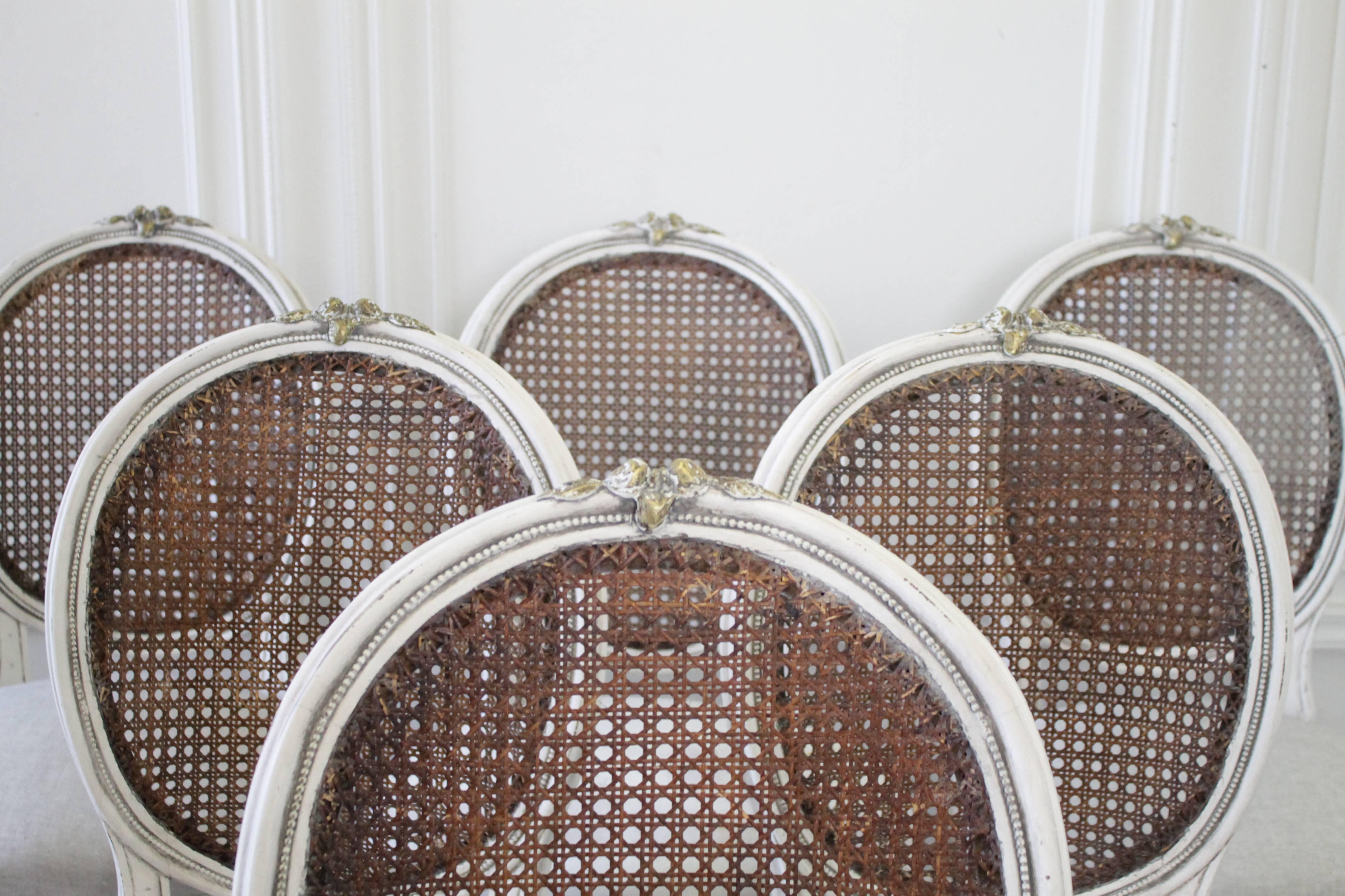 Beautiful set of six French cane back chairs, with painted frames finished in a soft oyster white, with hues of greys, browns and natural wood tones. Very solid and sturdy ready for everyday use. The seats have an eight way tied spring and