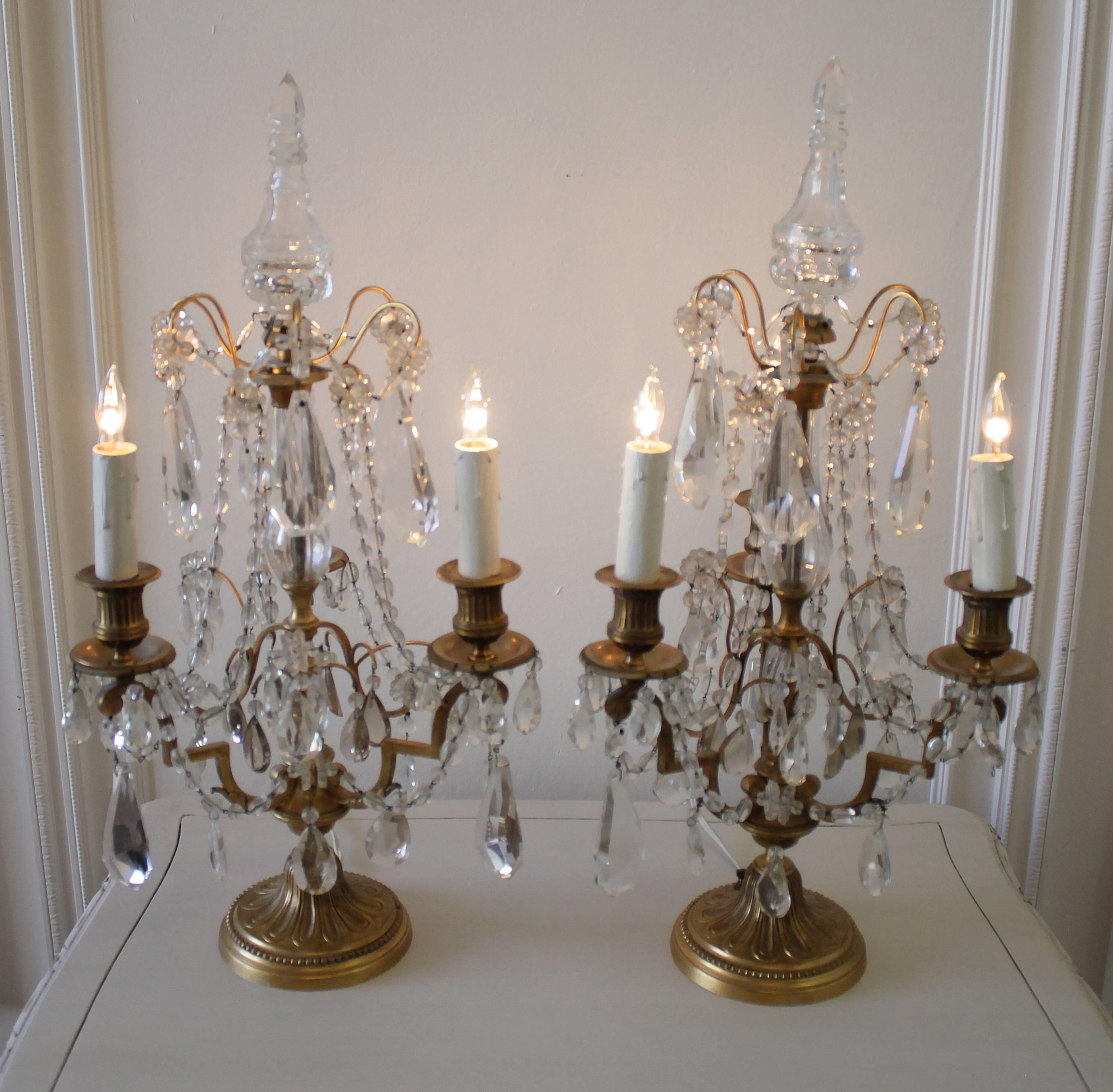 Stunning pair of three-light candelabra girandoles with clean crystal blown glass sections in the centers, extending to the top. Brass arms hold a lovely collection of clear crystal drops and soft pale topaz colored crystals and crystal florettes.