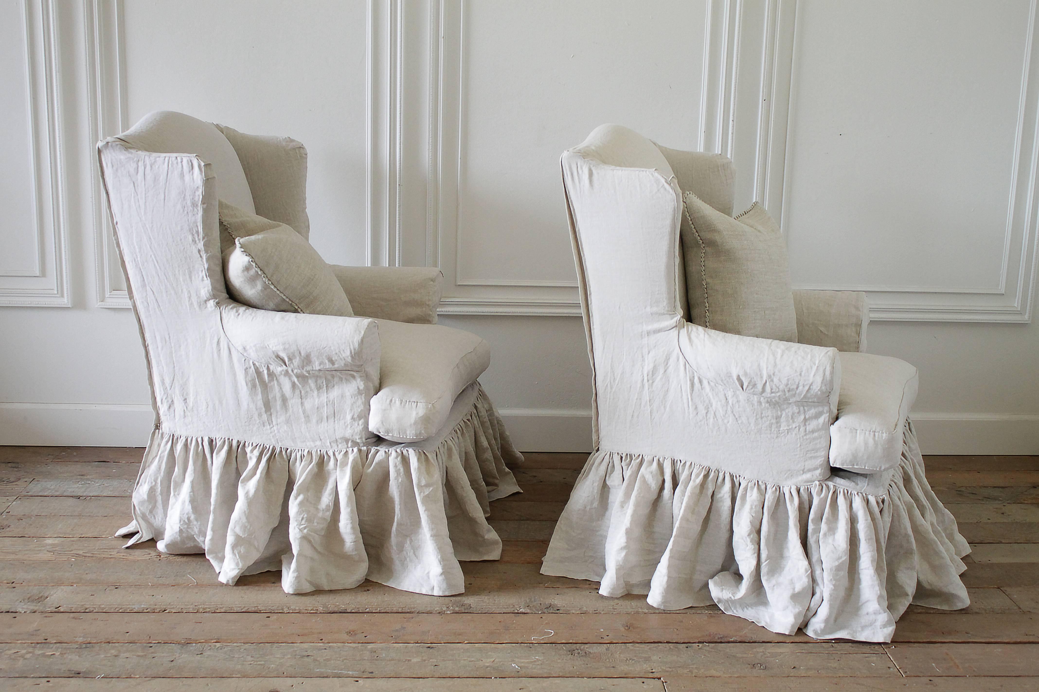 Fabulous pair of vintage wing chairs we have reupholstered in our organic greige irish linens. A custom double ruffled slip cover in the same greige linen, features a soft and squishy down cushion with flange edge and pleated ruffle corners. Chairs