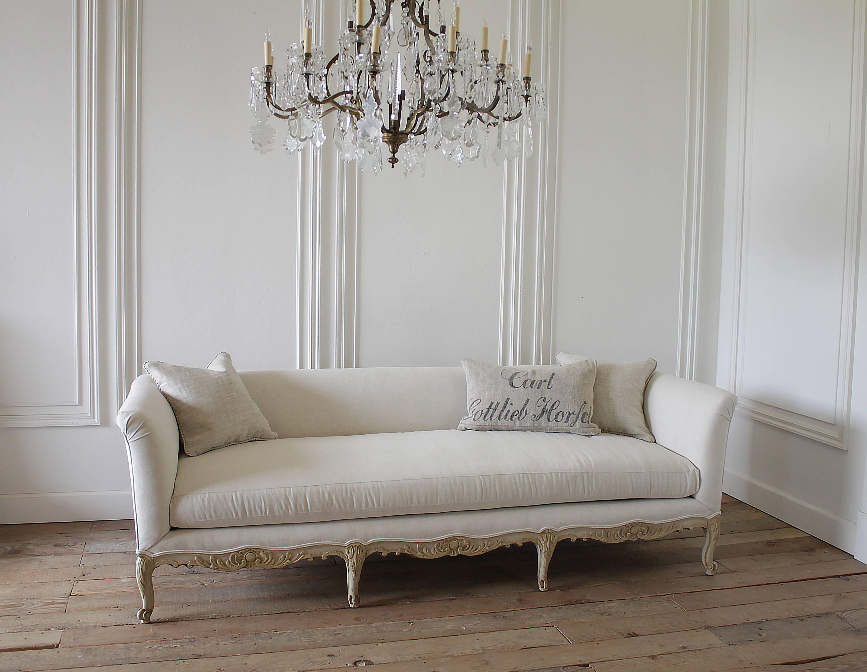 Beautiful antique sofa with Louis XV style painted legs in soft grey tone and golden linen colored highlights. Slightly distressed with wood tones peeking through the vintage patina paint. We have reupholstered this in our 100% pure Belgian organic