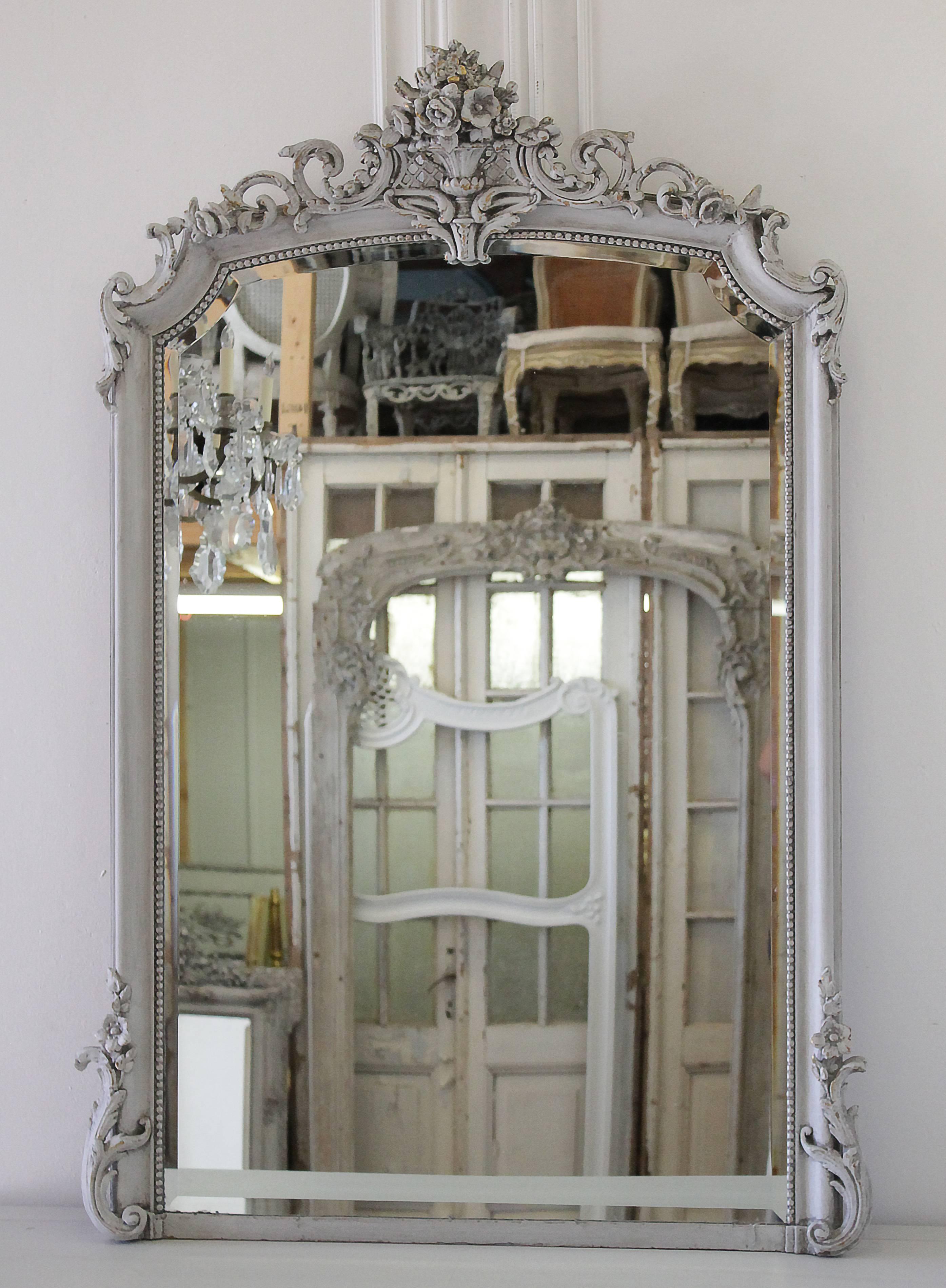 Beautiful antique mirror painted in our French Cobblestone grey finish, with distressing, and a hand glazed finish. Original bevel mirror shows subtle signs of age throughout. Large urn with roses spilling over into scrolls and more roses with a