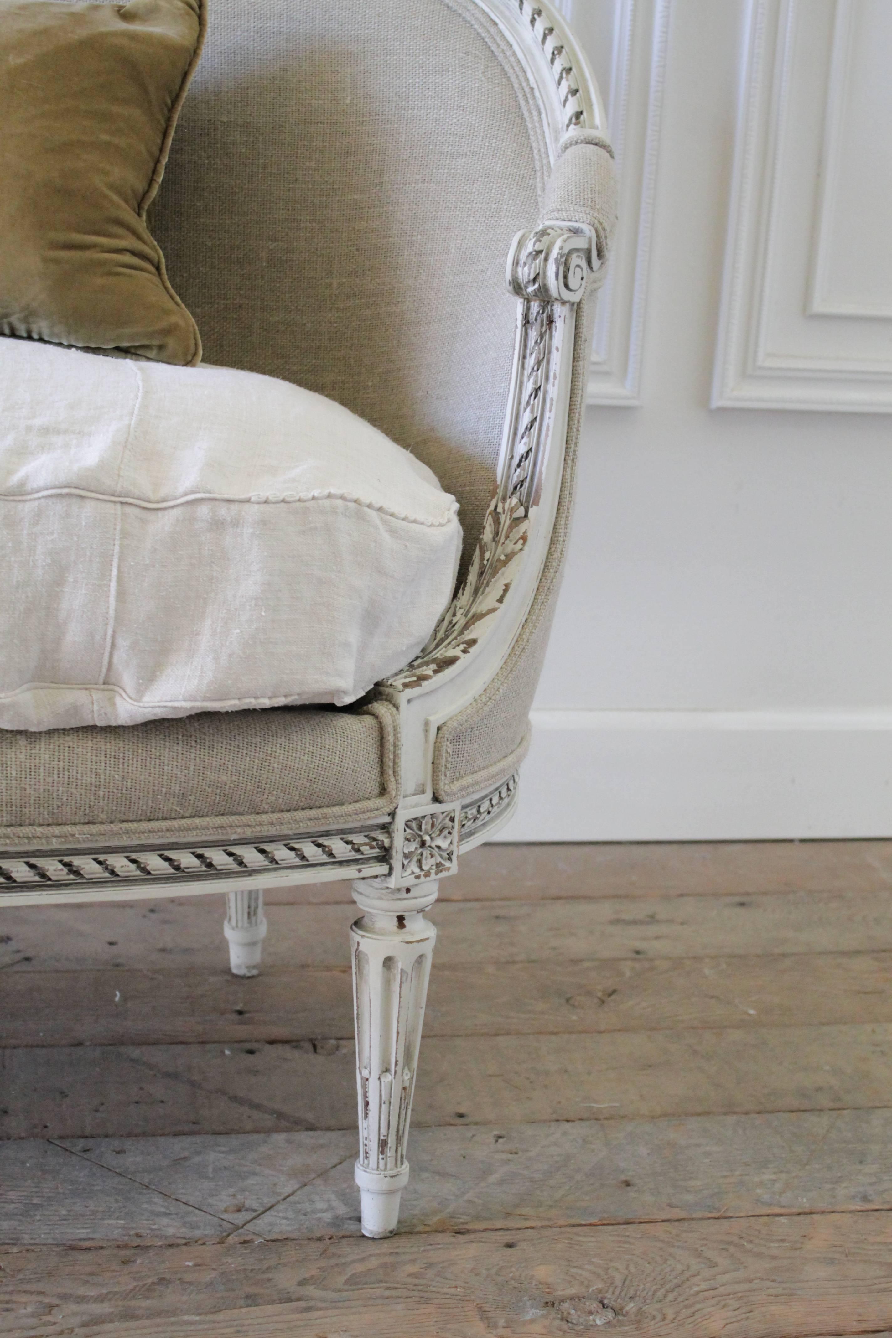 Beautiful antique French settee in the Louis XVI style, is finished in our oyster white with antique patina. All of our finishes are hand distressed to give the look of an aged finish. The settee has been reupholstered in an imported organic Irish
