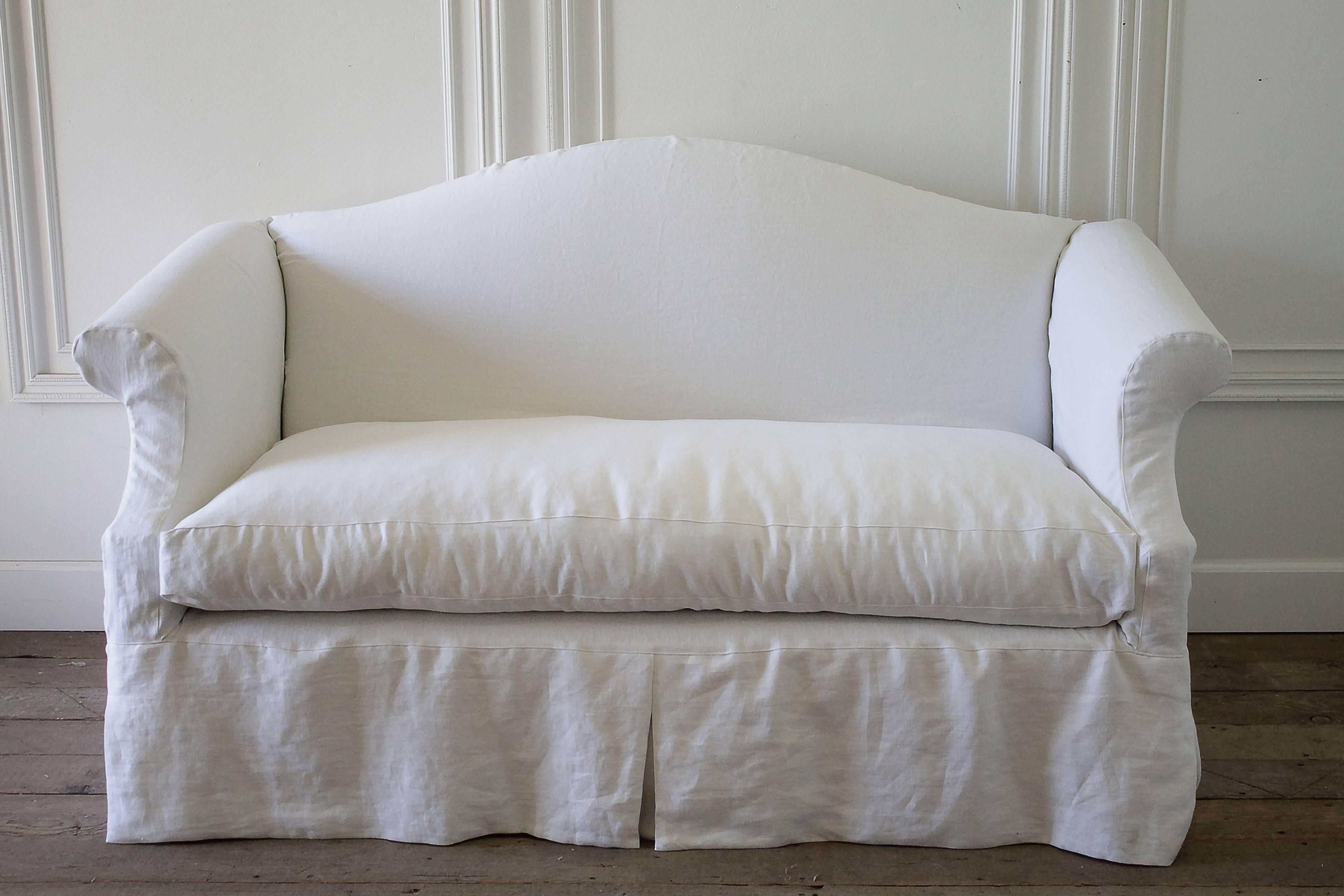 This vintage sofa has been slip covered in a wash Belgian Linen, soft white color. The seat cushion is a comfortable down wrap, and has a removable cover. The slip cover can be washed regularly. Finished with a top stitch edge. Legs are solid wood,