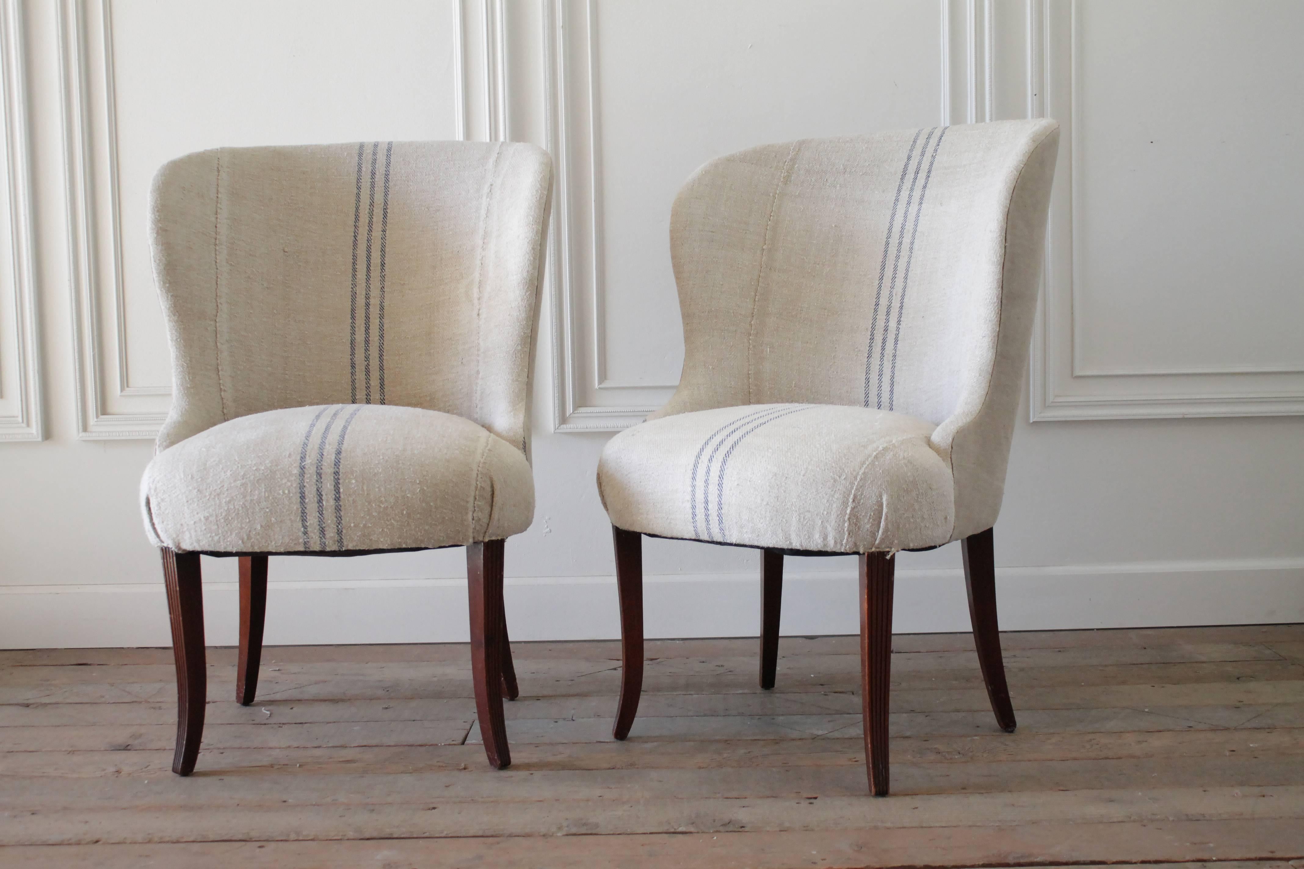 Stylish Ralph Lauren Wing chairs with solid wood legs, reupholstered in an antique French grainsack material. The grain sack we chose have a light oatmeal color background with a faded blue ticking stripe down the center. A very thick nubby texture