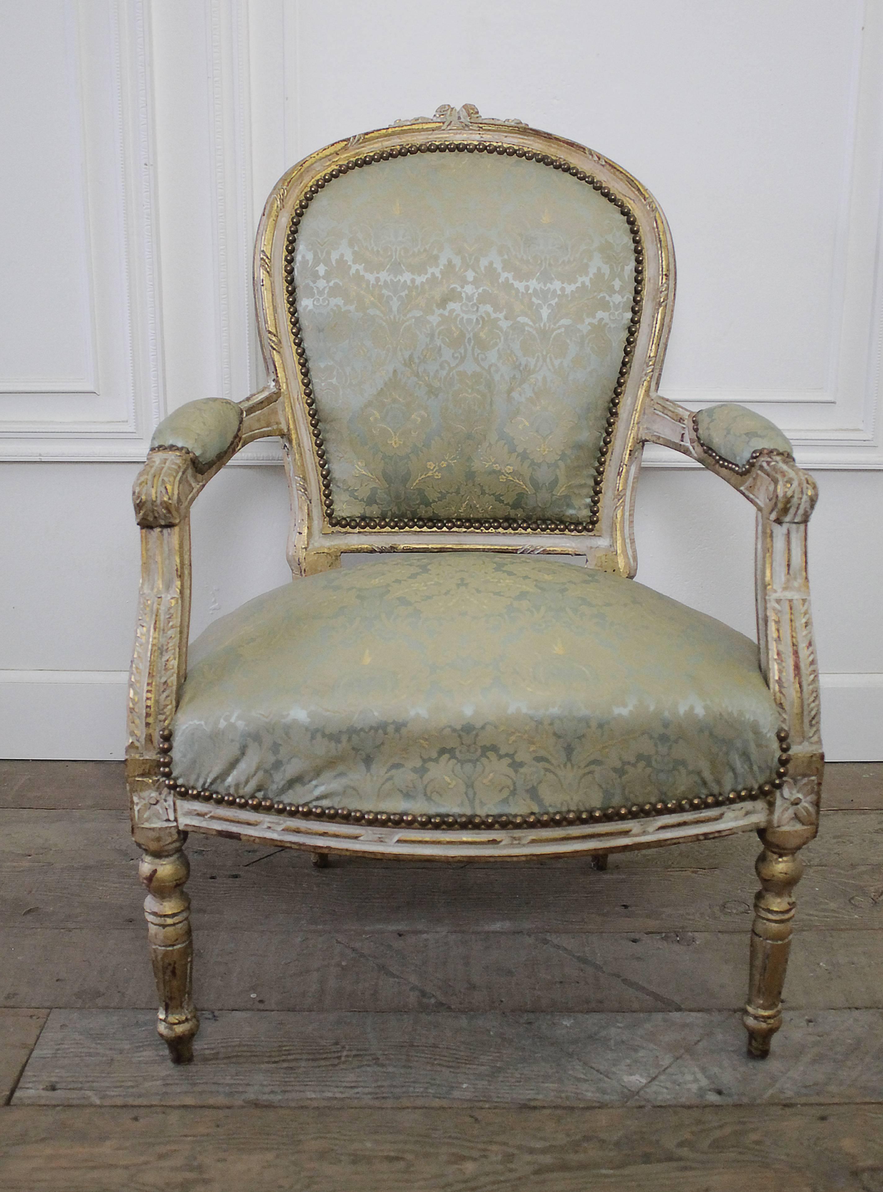 Beautiful French Louis XVI style gilt chair with original upholstery and nailhead trim. The frame of the chair has a wonderful worn patina, with chipping and fading througout. Very petite rose and leaf carvings on the top of the chair, with an