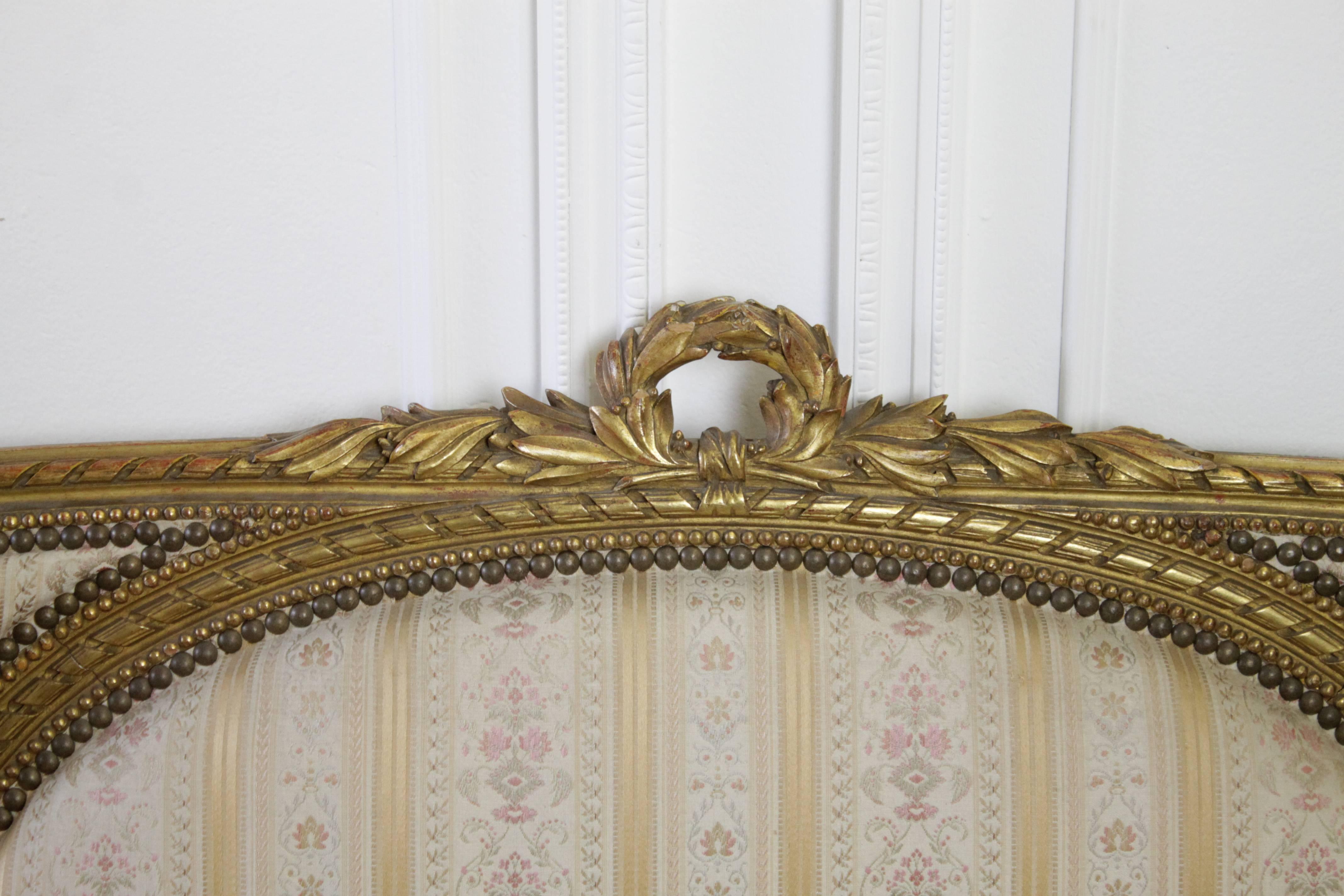 French Louis XVI Style giltwood sofa with original upholstery, circa 1920. The frame of the sofa is in good condition, with flakes of gilt chipping away here and there, condition is what one would expect of this age sofa. The sofa seat has the