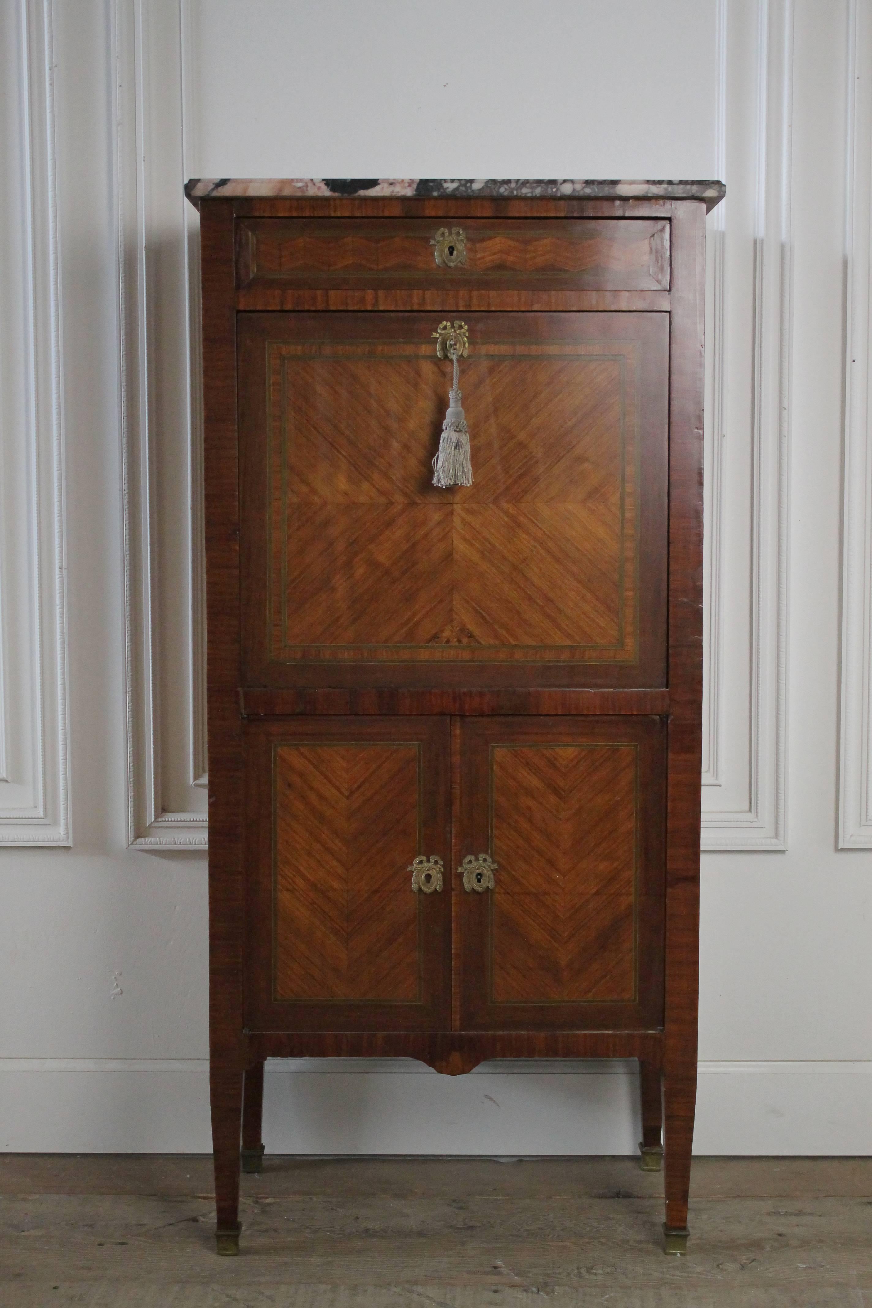 Lovely French abattant secretaire with beautiful inlays. Original brass hardware and working locking key and hassle.
Legs are sturdy, drawers and doors open with ease. The key work on the drop down portion of the secretaire.
Marble top is in good