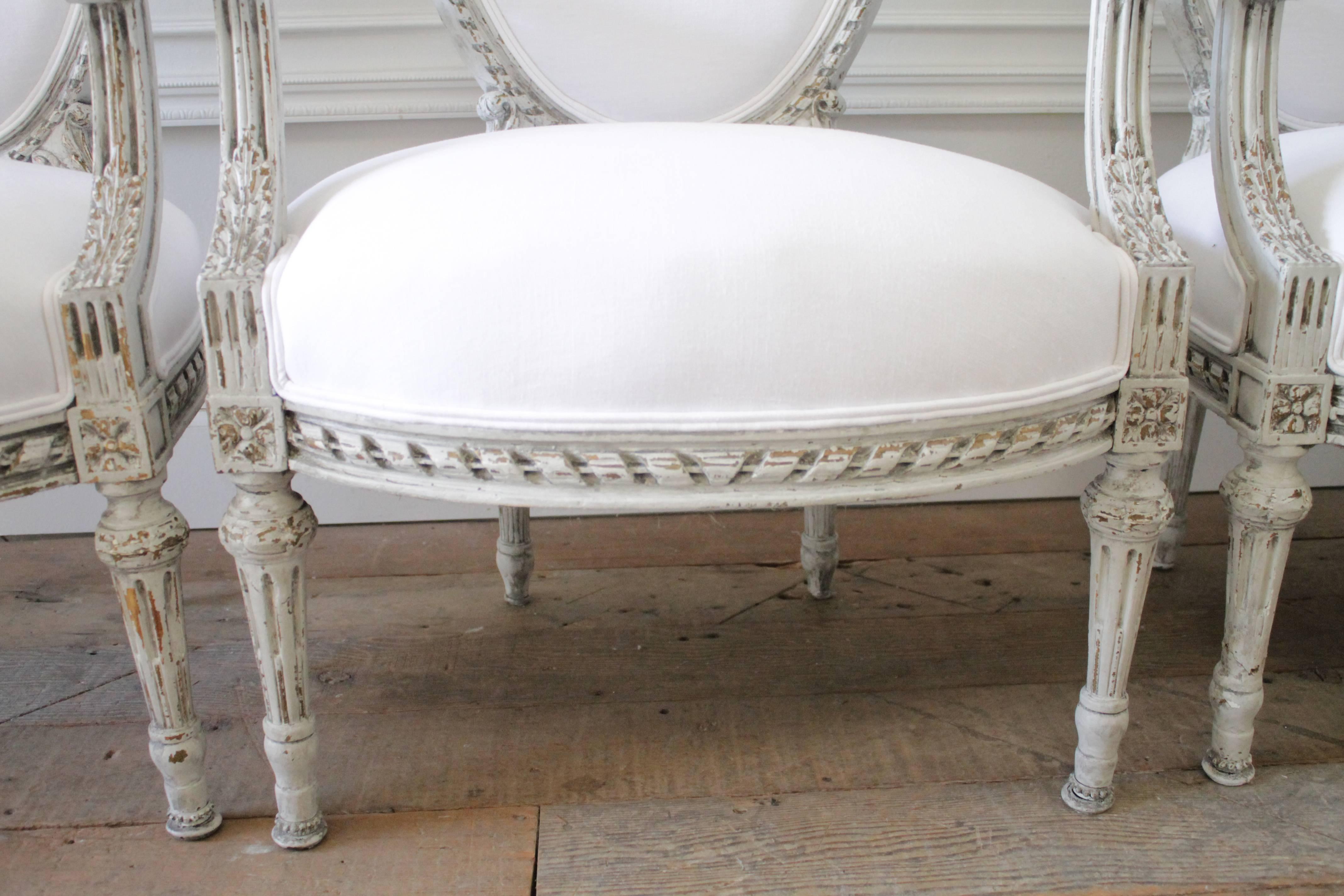 Four Painted and White Linen Upholstered Louis XVI Ribbon Carved Armchairs 1