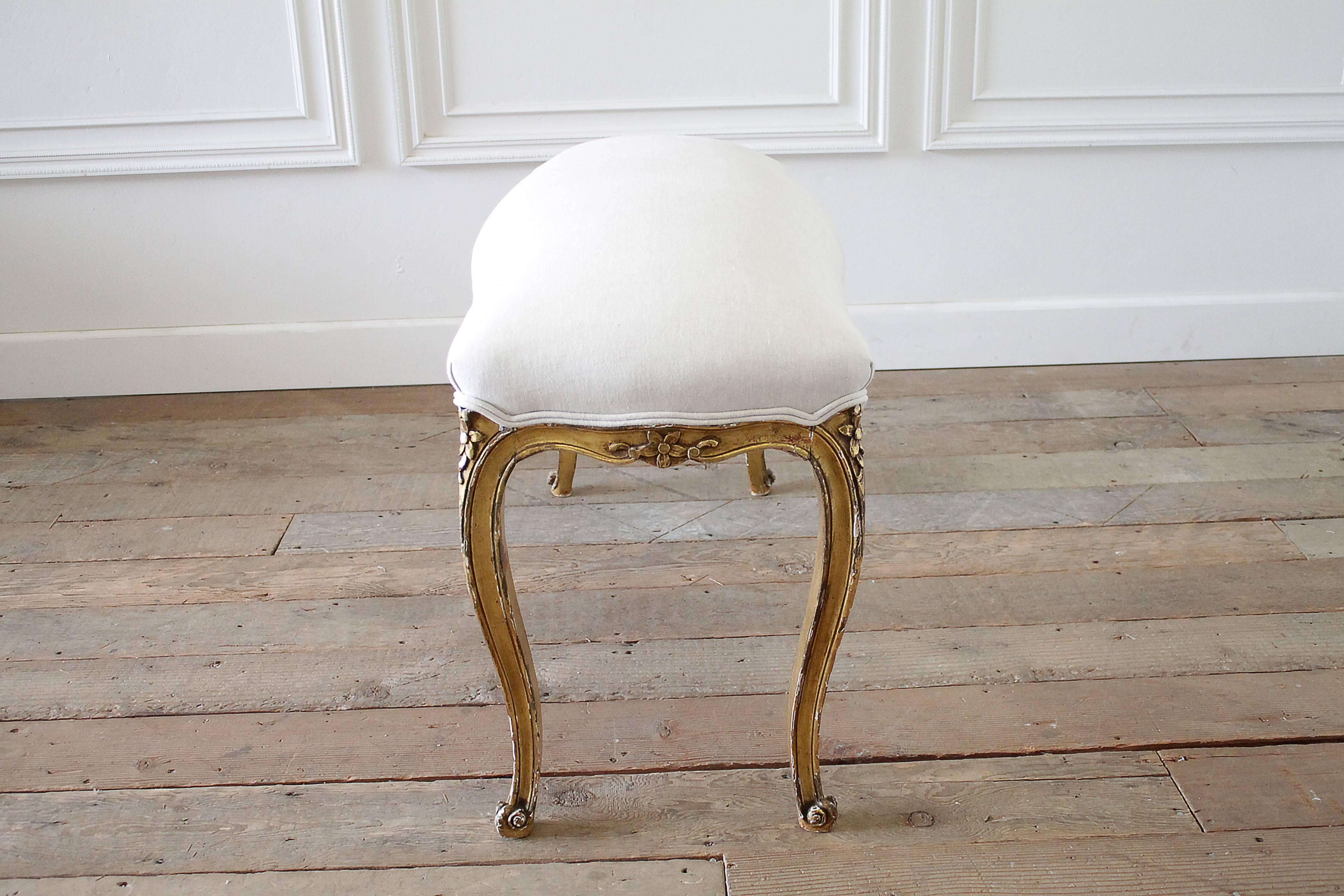 Beautiful carved Louis XV style giltwood bench we have upholstered in our Organic Irish linen, and finished with a double welt. The frame is sturdy, and shows signs of a weathered finish. Very nice patina, and linen is a light oatmeal
