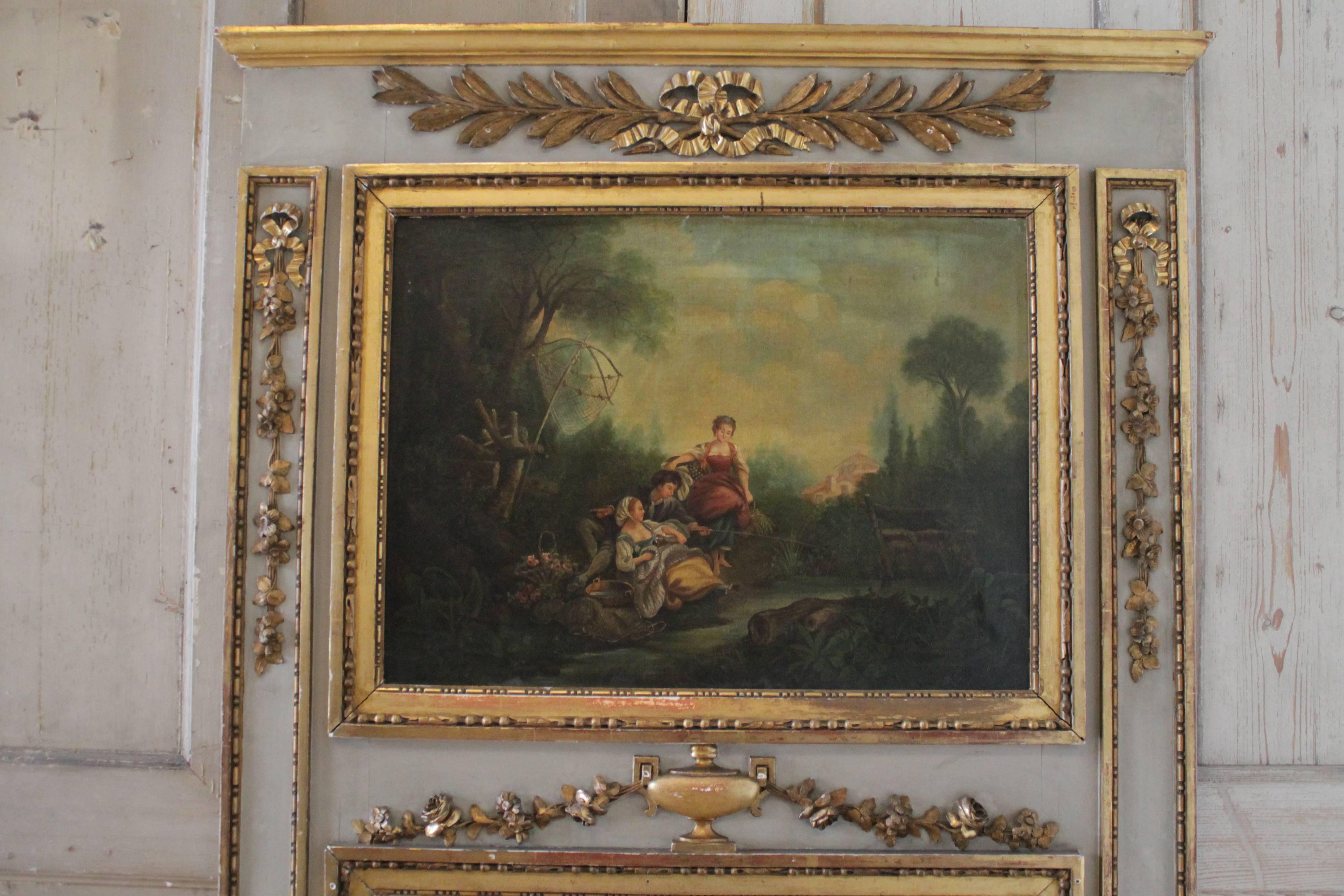 Marvelous 19th century French painted and parcel-gilt trumeau. Having a lovely carved urn, swag and ribbon details. Featuring oil on canvas of landscape with figures and an excellent aged patina.
Color of the frame is a muted grey with