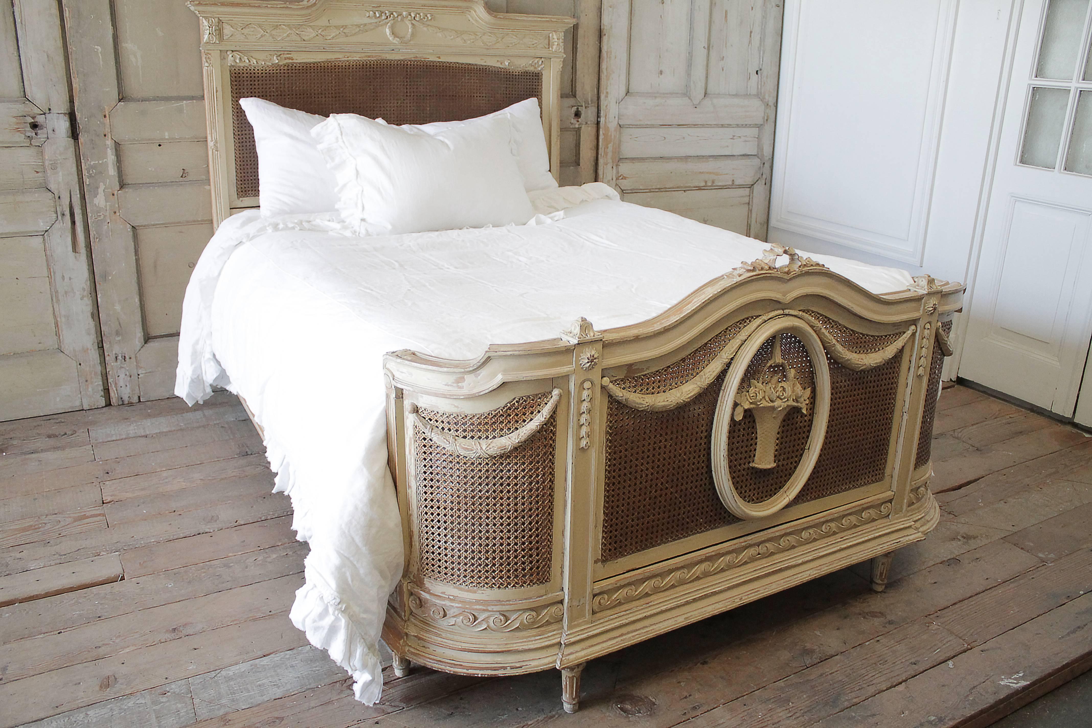 Beautiful original painted French country style cane bed. Creamy colored, with wonderful aged patina, creamy white and wood tones peeking through the paint and double caned footboard. Cane is in good condition, no major holes or breaks, just a