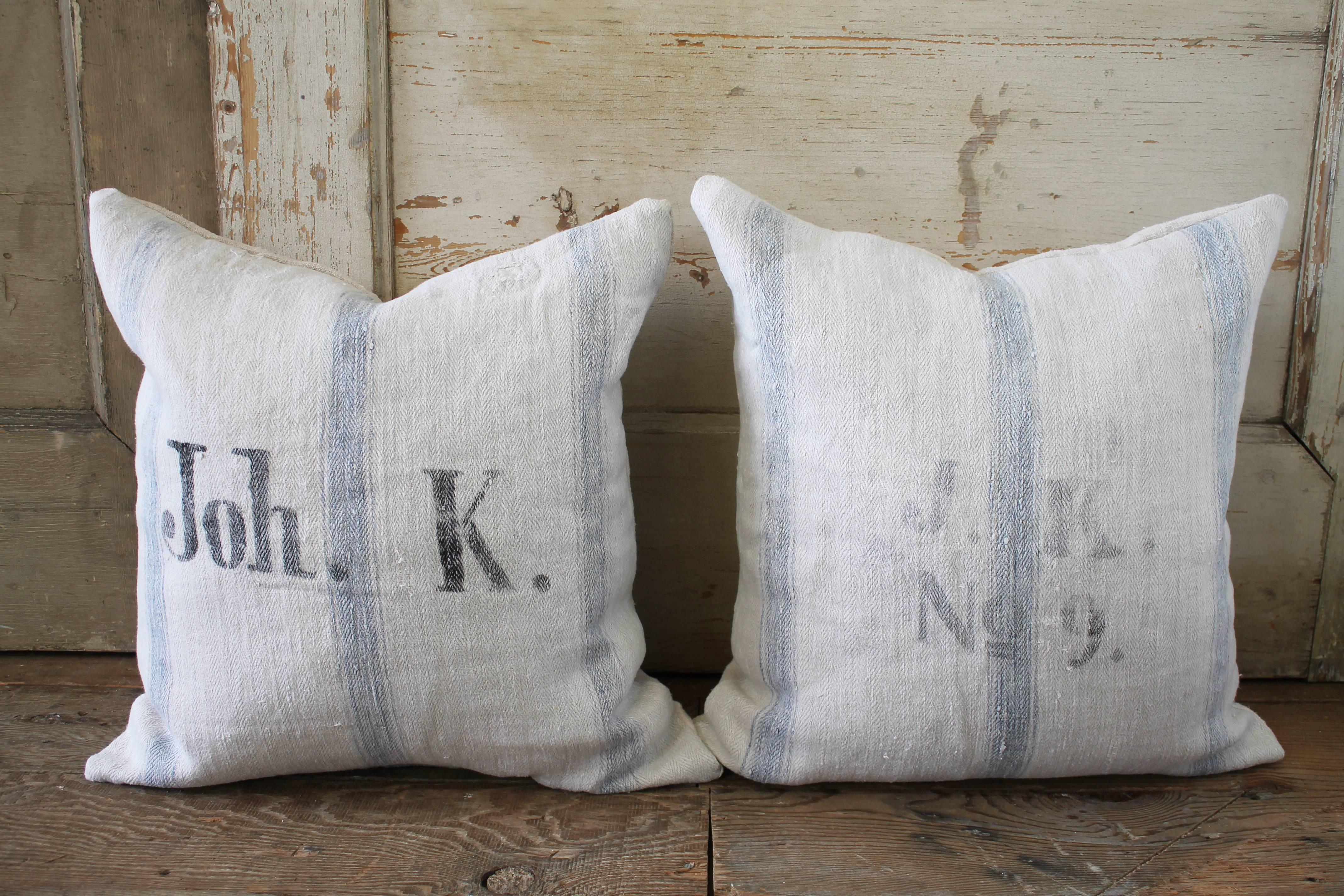 Lovely pair of grain feed sack pillows from Europe. We custom-made these out of the original antique feed sacks, with zipper closure and overlocked edges.
The fronts are a soft pale oatmeal color with pale Swedish blue stripes and original