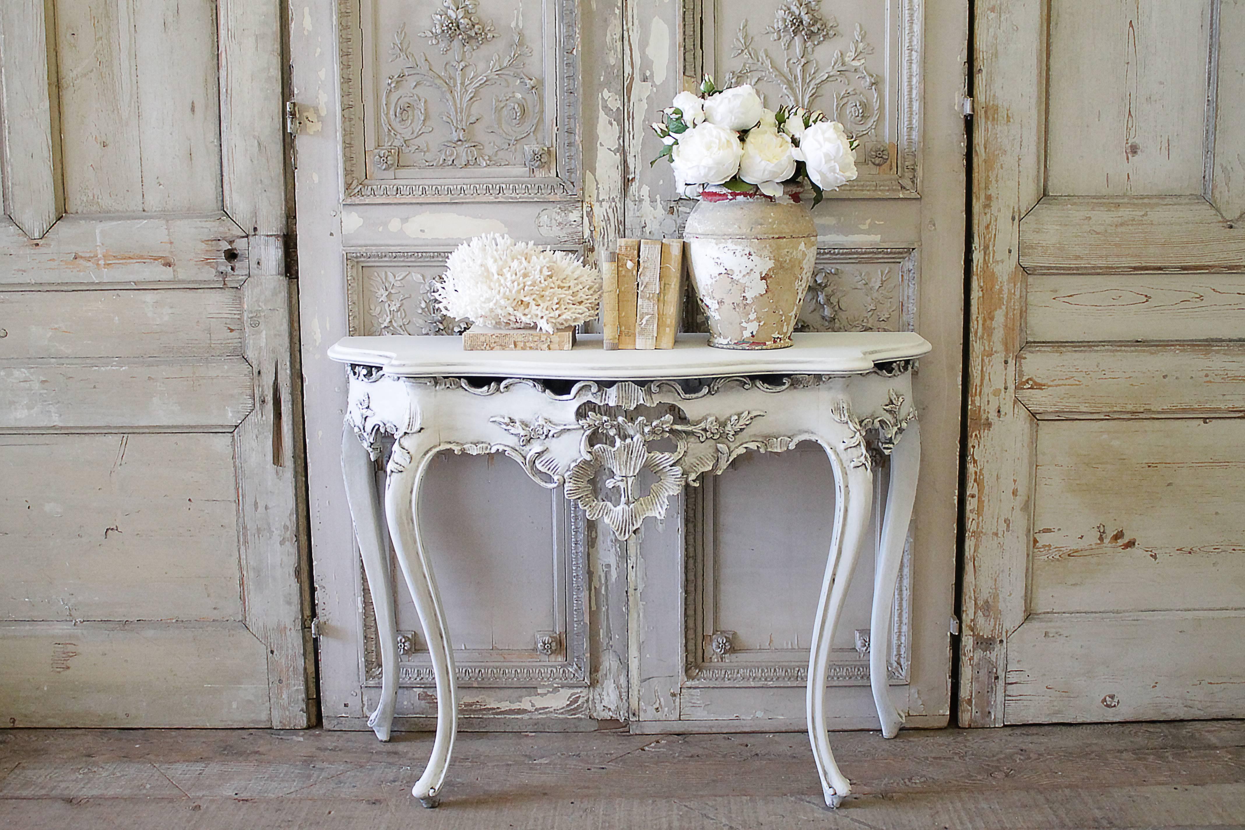 Painted in a soft oyster white with hand glazed finish. Gilt finish peeking through the paint on areas where there is distressing. Louis XV style with carved decorative details, and Classic curved legs.
Measures: 45