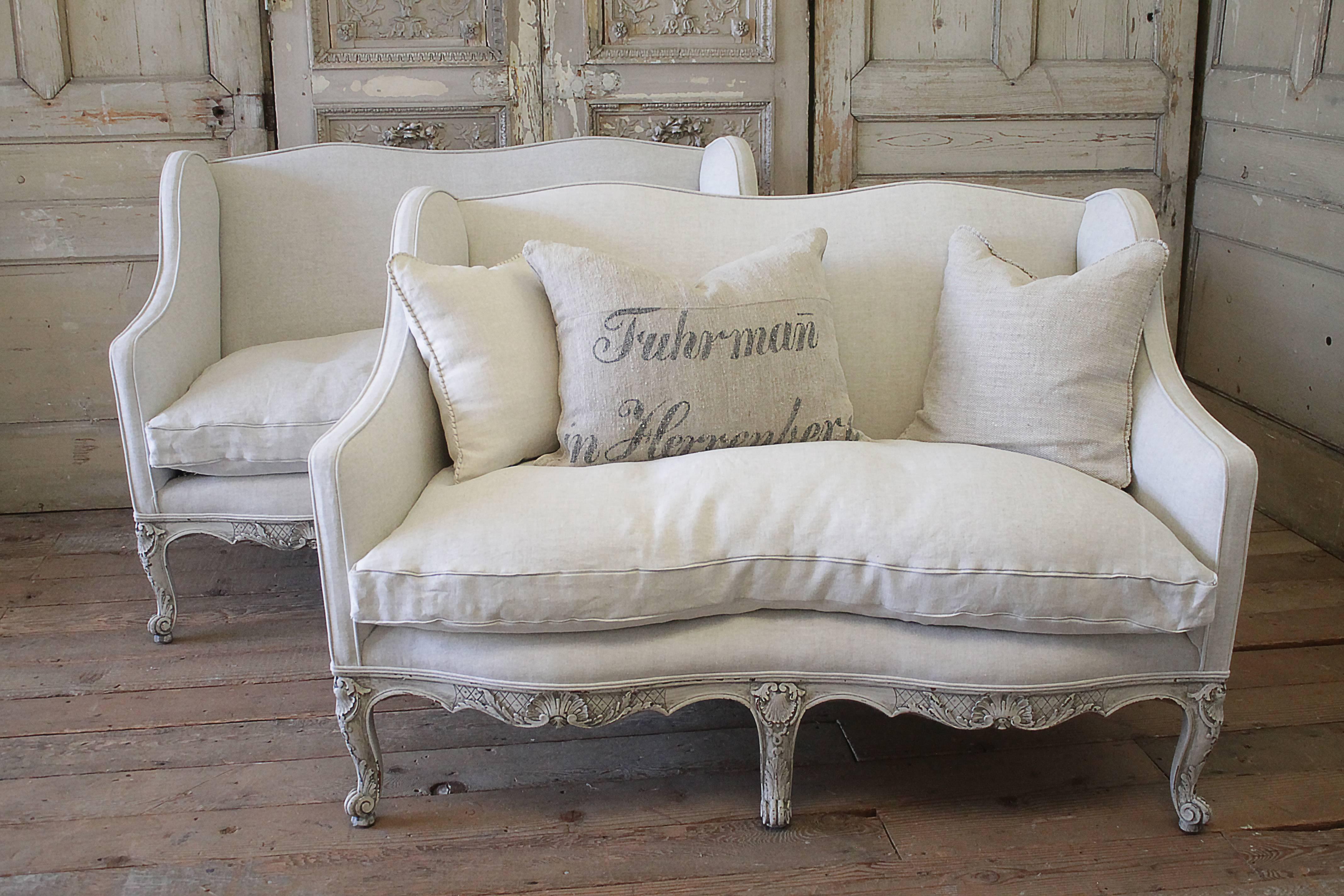 Beautiful painted pair of vintage settees from the 1930s. The base is solid carved walnut that has been painted in our soft oyster white finish, with subtle distressing, and finished with an antique hand rubbed glaze. The finish has a grayish tone.